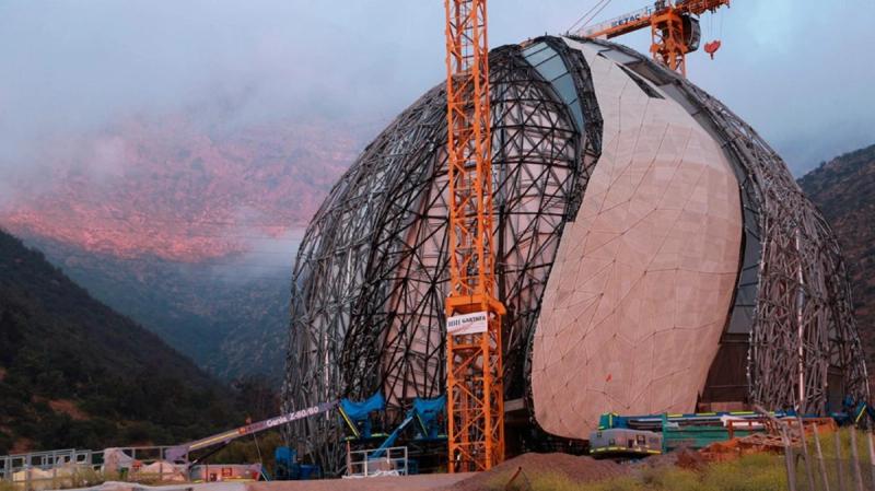 Templo Bahá’í en construcción, con grúas y la cordillera al atardecer