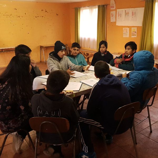 Prejóvenes conversan y estudian juntos en torno a una mesa