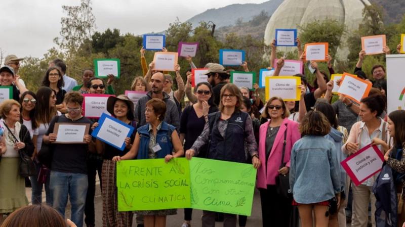 Personas sostienen carteles por el clima frente al Templo Bahá’í en una acción interreligiosa