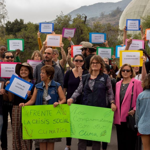 Personas con carteles sobre la crisis social y climática frente al Templo