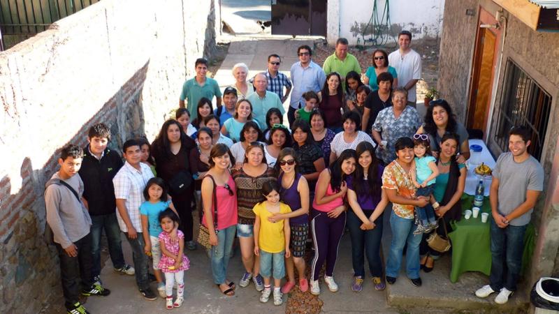 Numerosas personas de todas las edades reunidas en el patio de una casa, comunidad bahá’í de Peñalolén