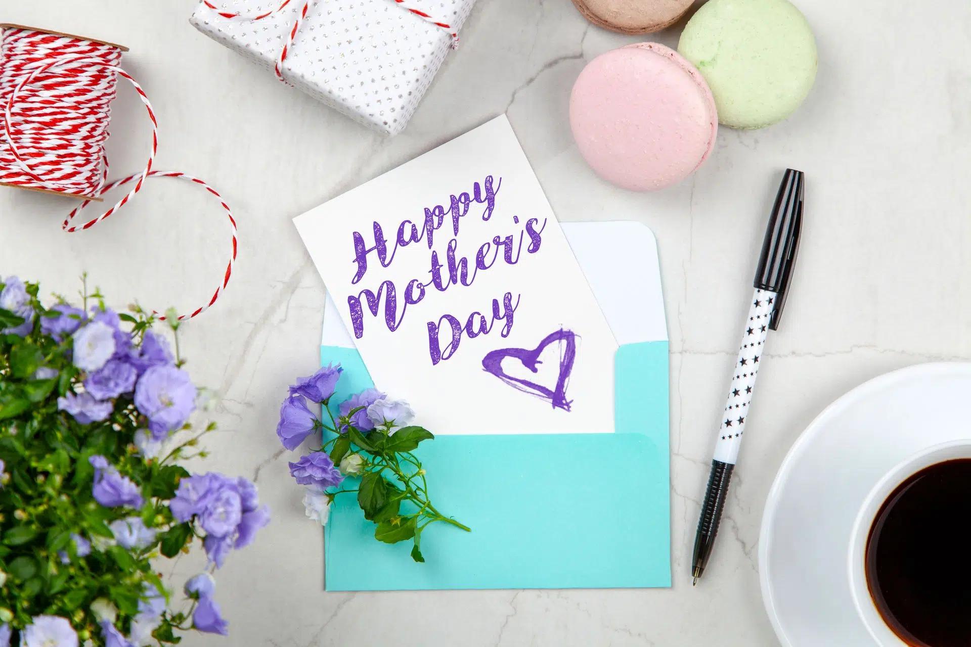 Creative Mother's Day card setup with flowers, coffee, and macarons on a marble table