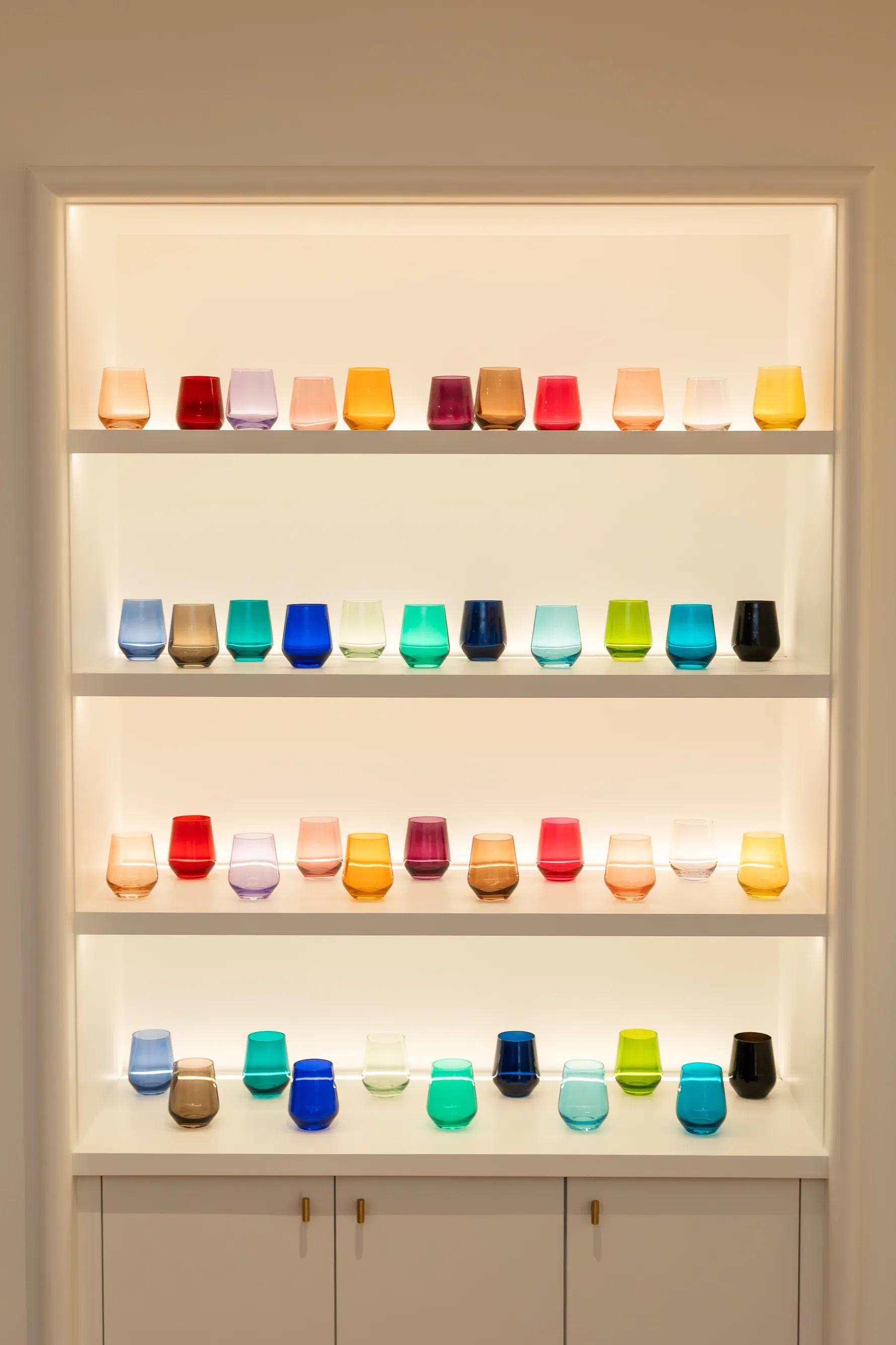A shelf filled with stemless Estelle colored wine glasses