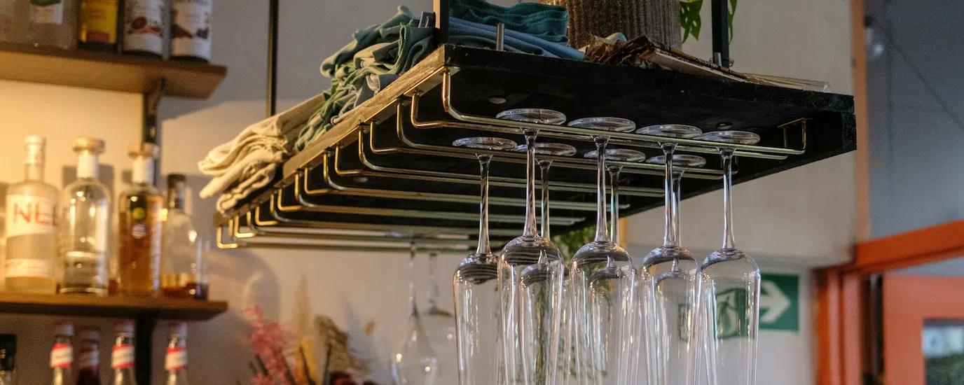A metal wine glass rack with champagne flutes hanging on it inside a kitchen