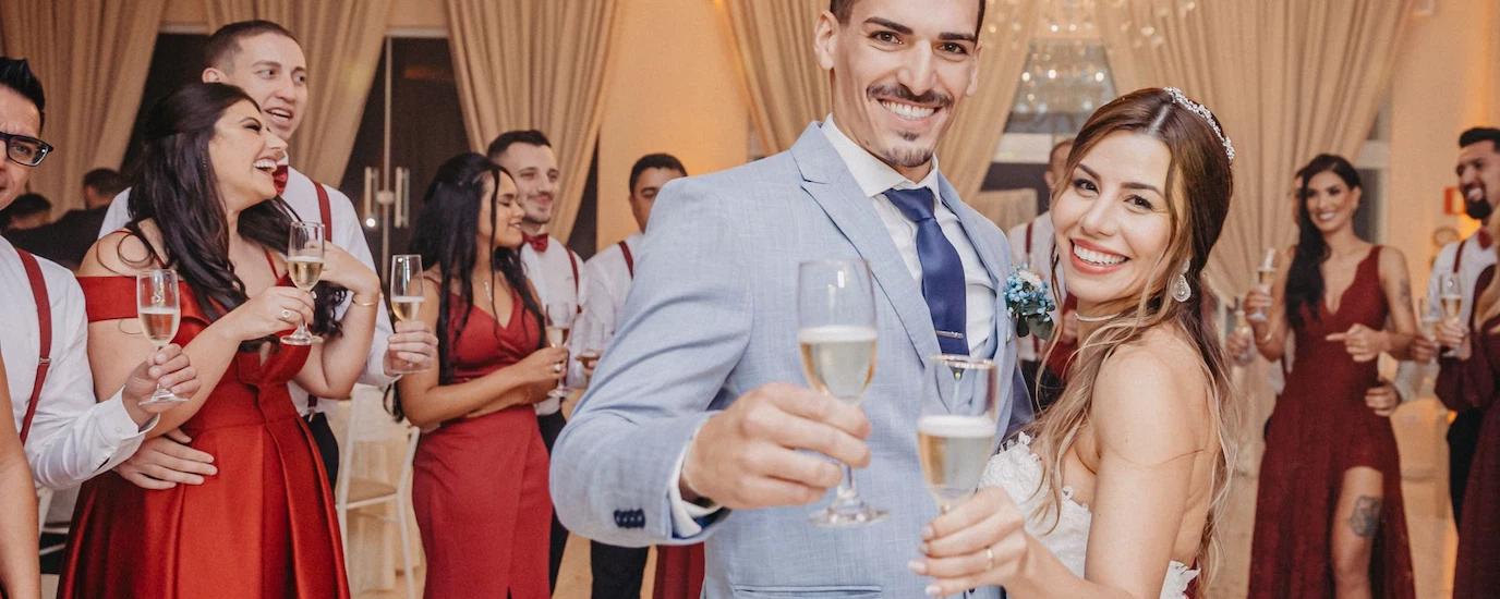 Newlywed couple celebrating with guests at an elegant indoor wedding reception, toasting with champagne
