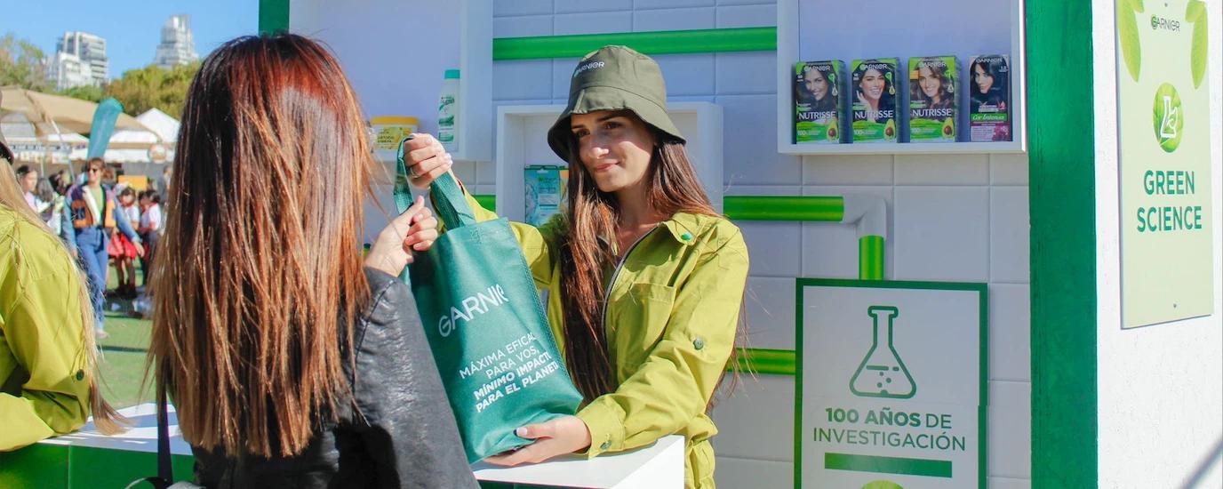 A brand's booth personnel handing a giveaway to an event attendee