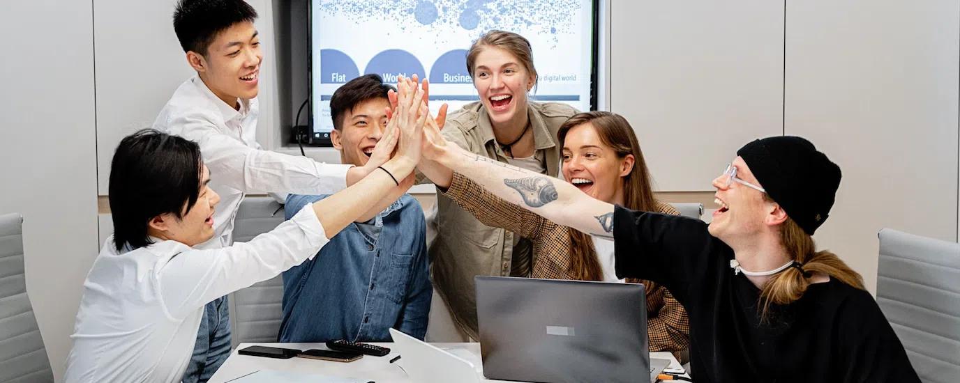 A diverse group of professionals high-fiving in a modern office setting