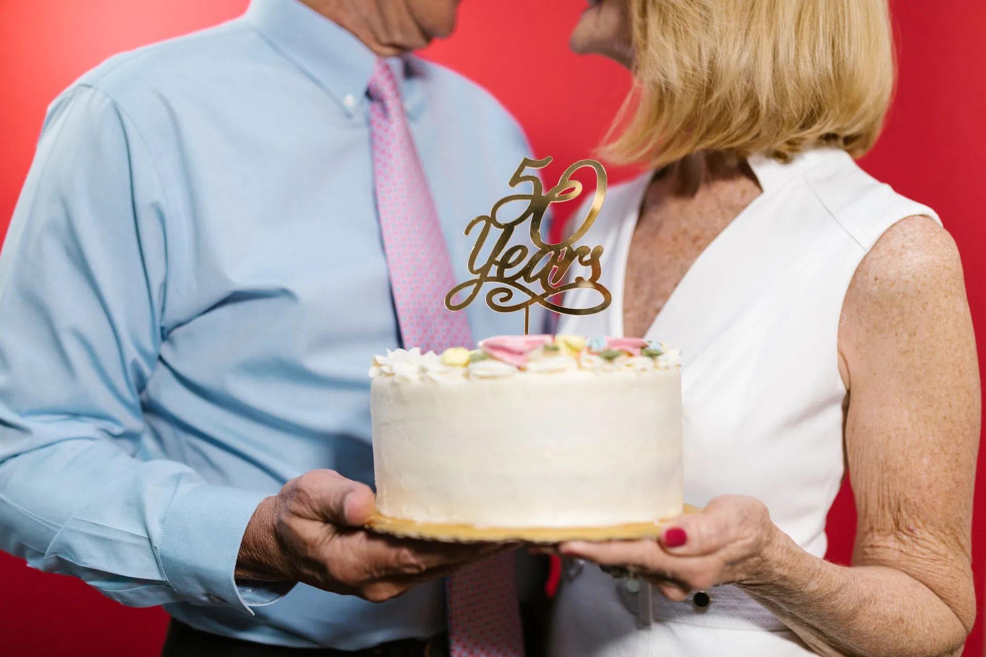 A couple celebrating their 50th anniversary with a decorative cake, symbolizing a lasting bond