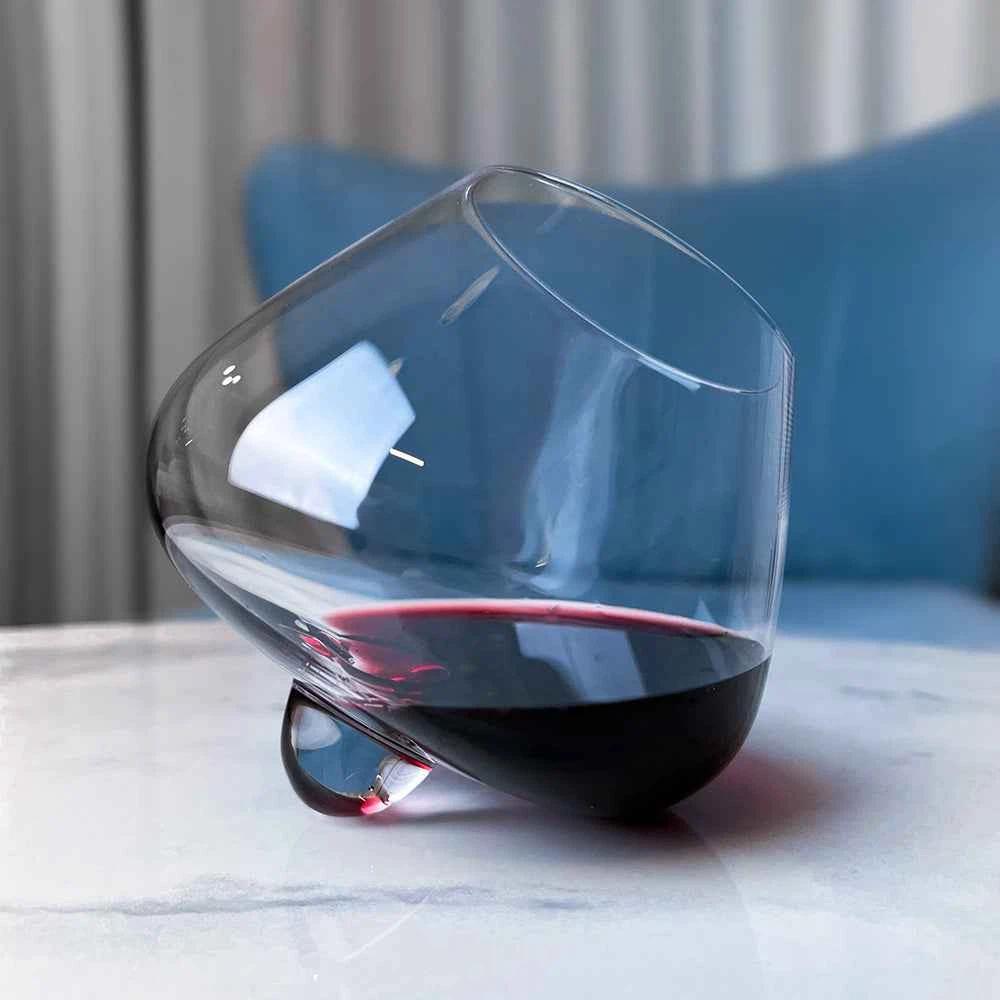 A closeup show of the Aequilibrium Wine Glass by Audacem, filled with wine and sitting on a marble table