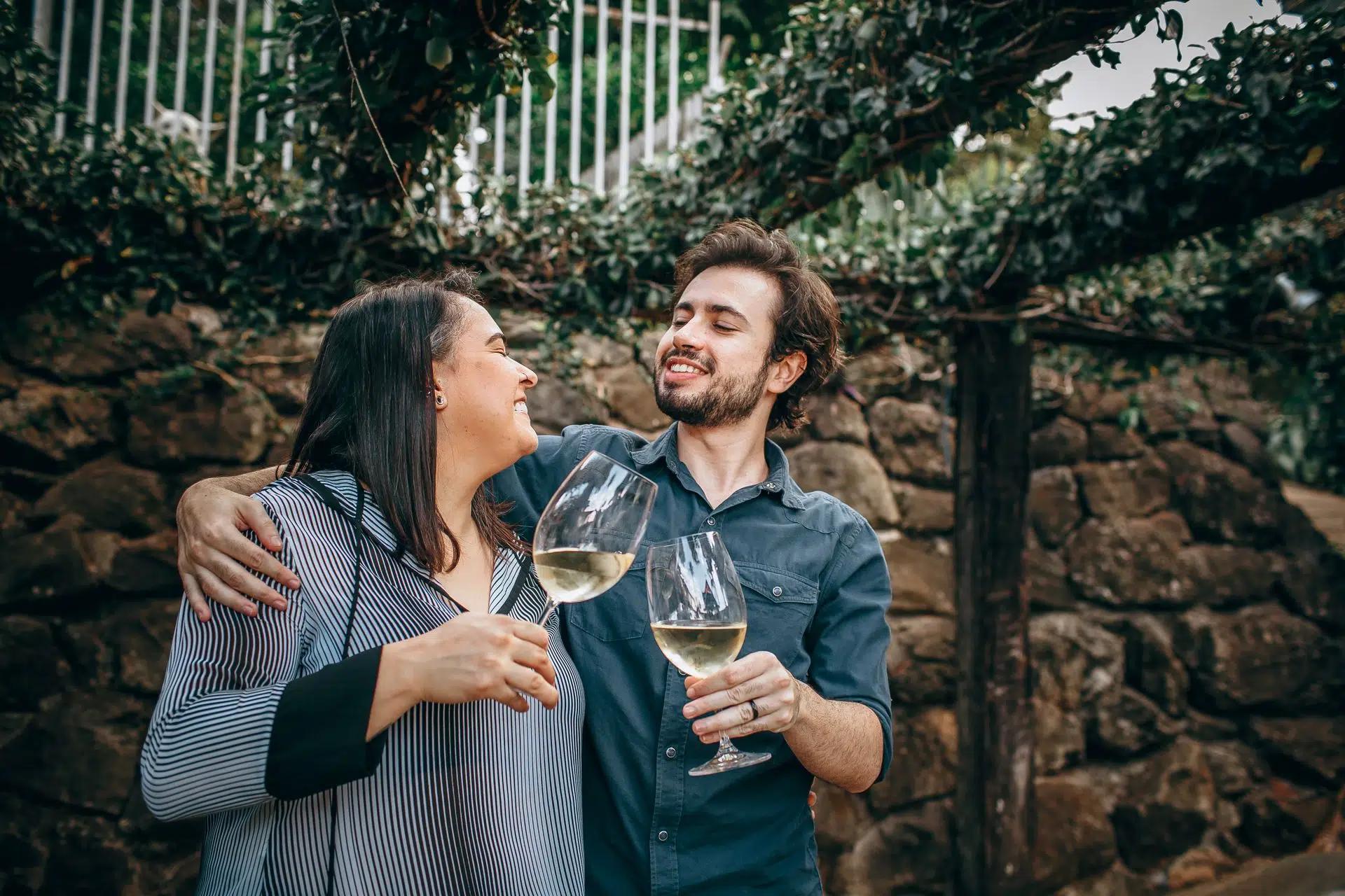 A joyful couple enjoys white wine outdoors, creating a vibrant celebratory moment