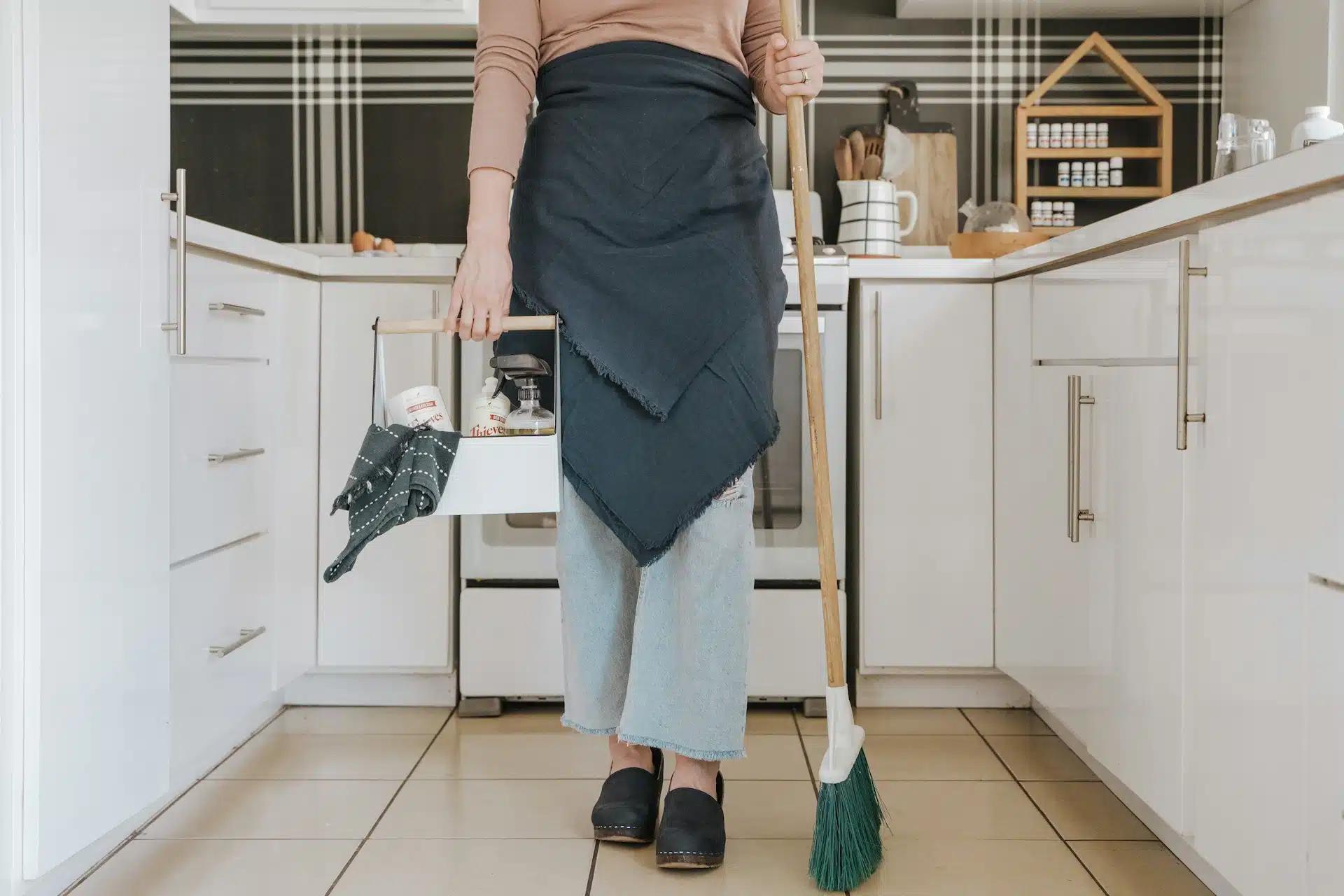 A cleaning personnel carrying cleaning tools in the kitchen
