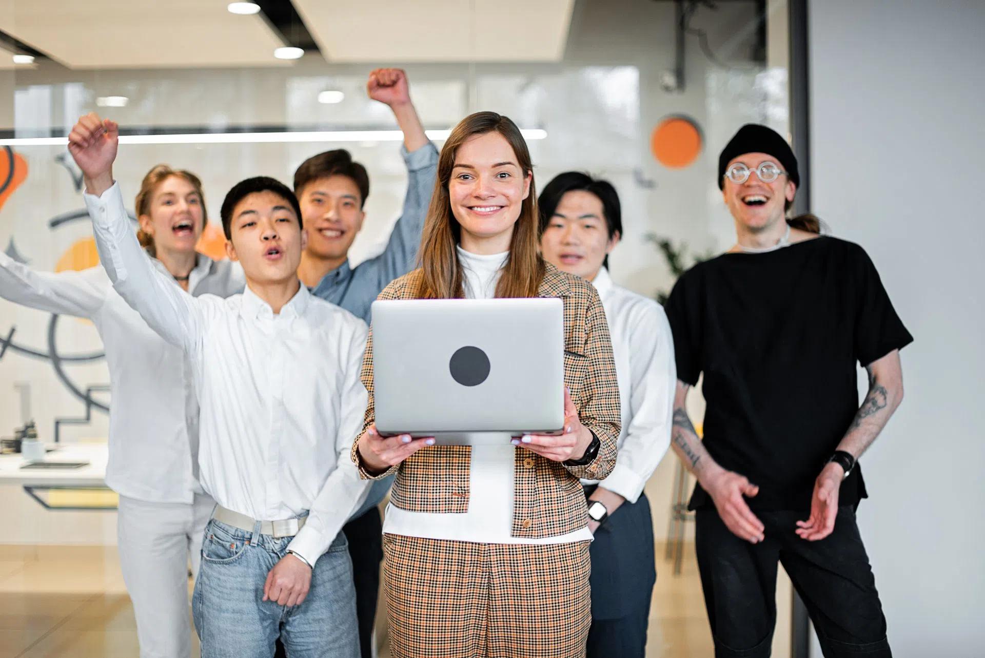 A cheerful, diverse team celebrates success in a modern office environment