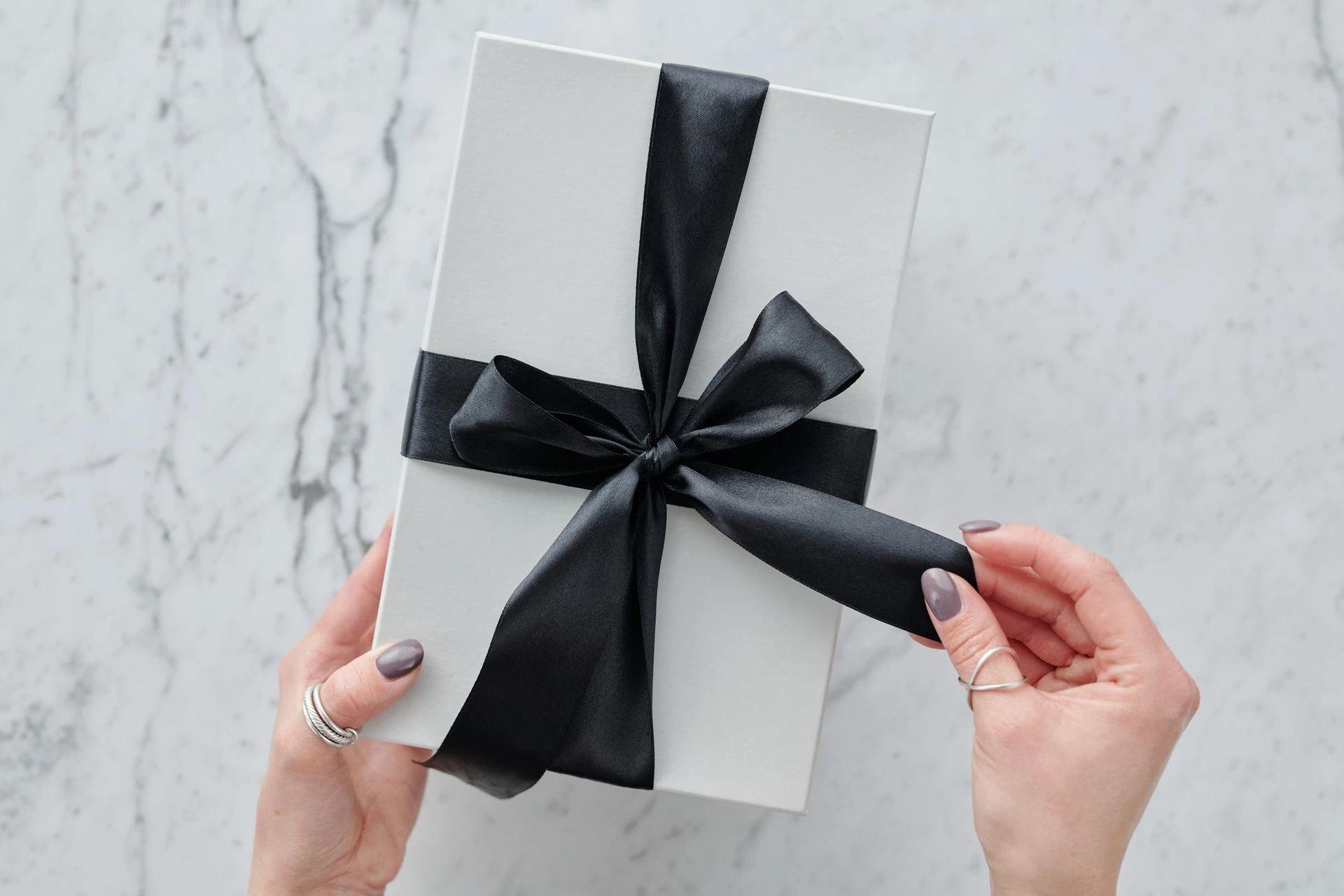 A sleek white present tied with a black satin ribbon, providing a touch of luxury