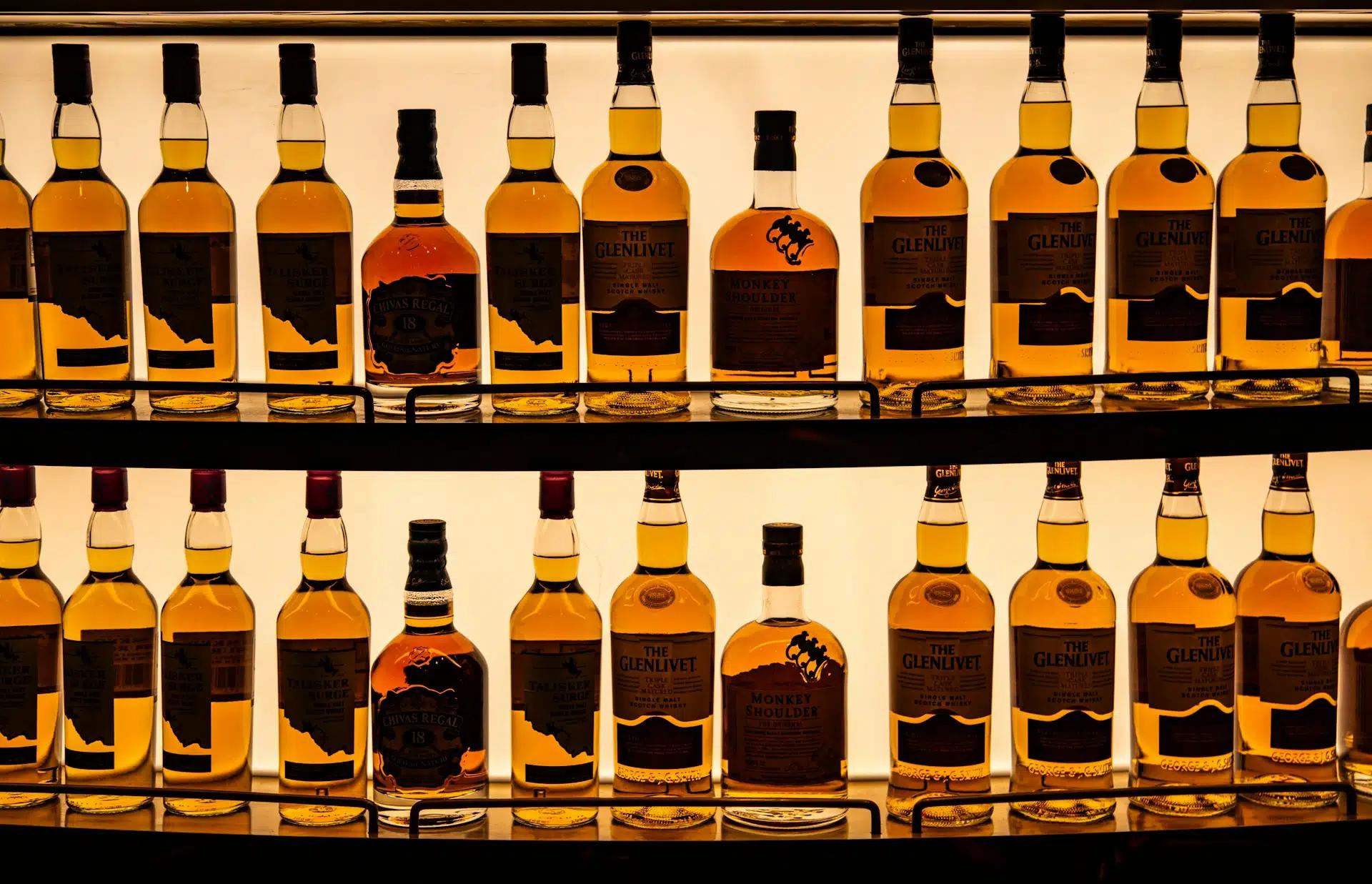 A shelf lined with different bottles of whiskey