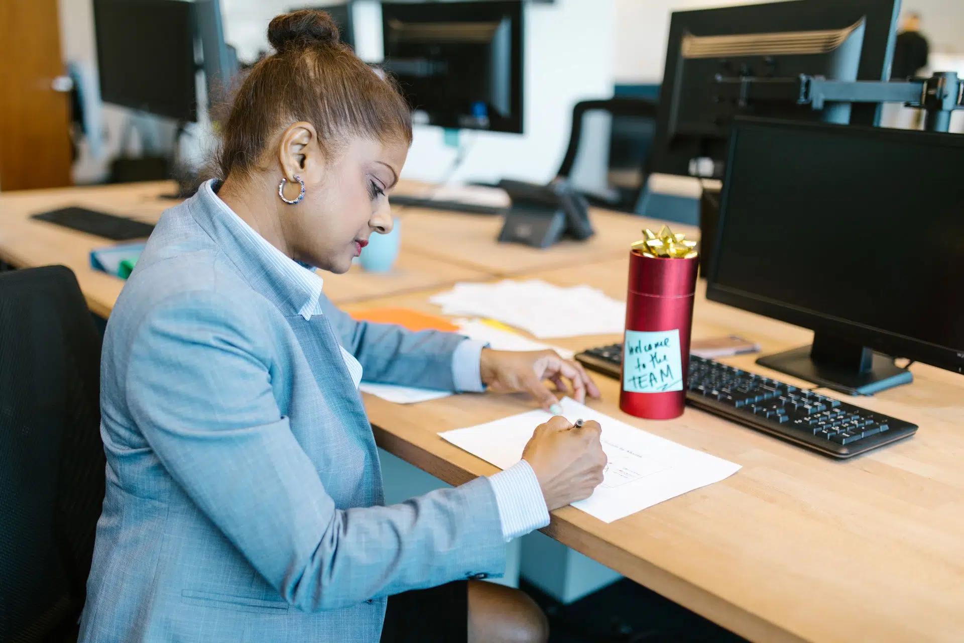 A focused woman working at her desk in a modern office setting with a welcome gift on display