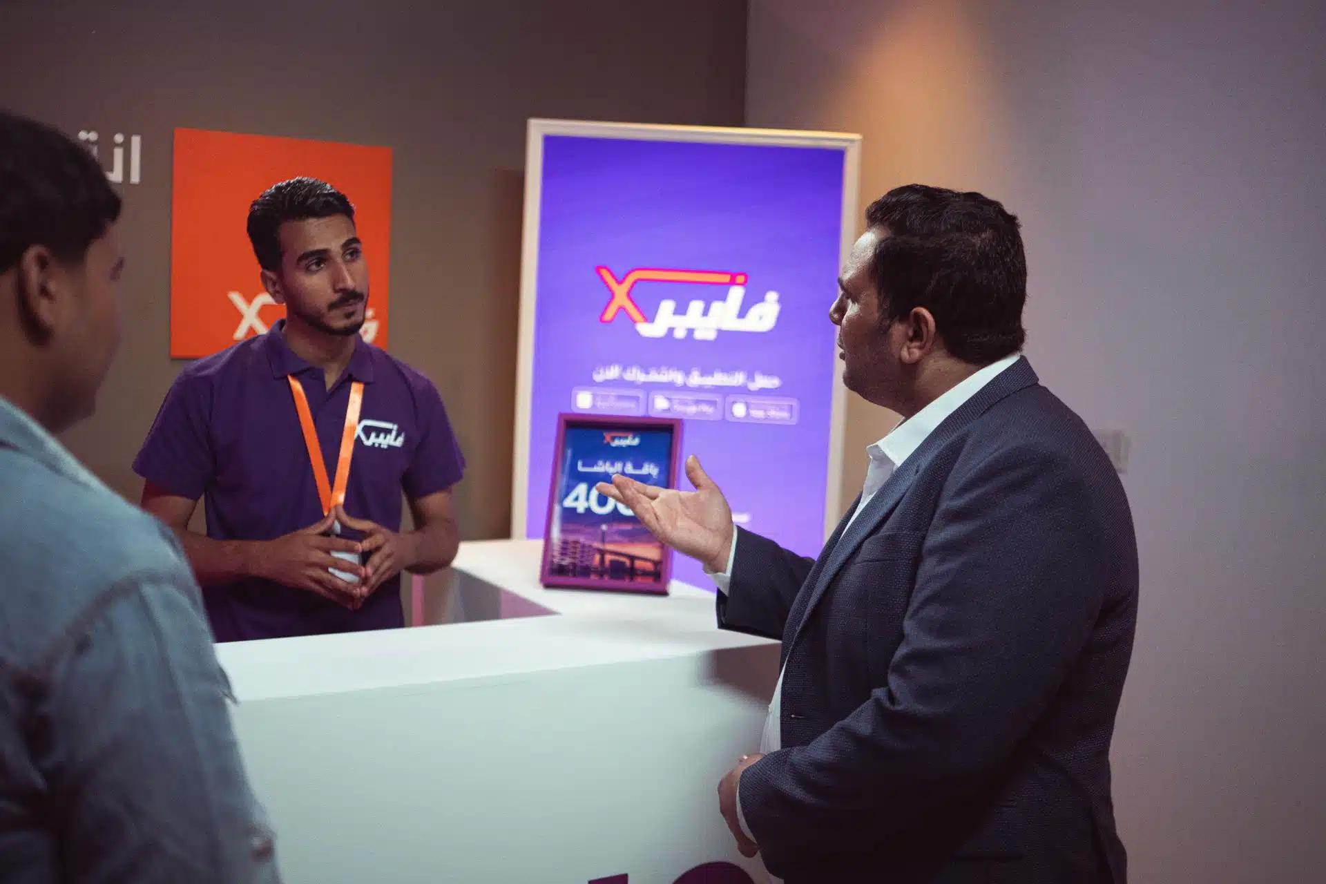 Engaging customer service interaction at a technology booth during an exhibit, featuring staff and potential clients
