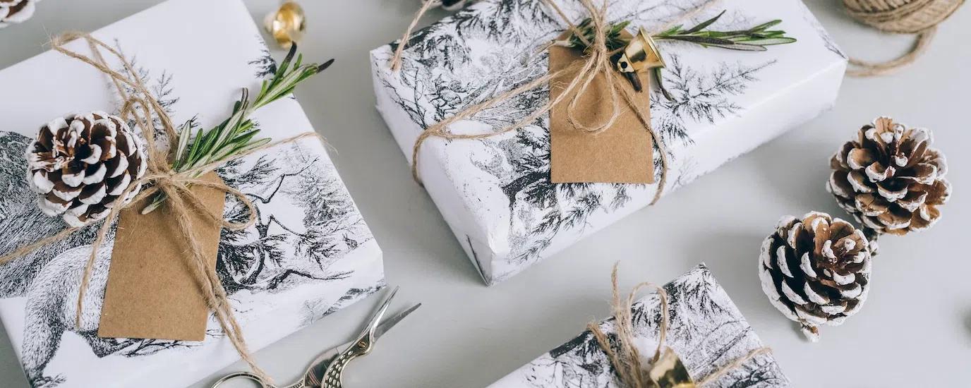 Beautifully wrapped Christmas gifts with pine cones, bells, and rustic elements in a flat lay composition.