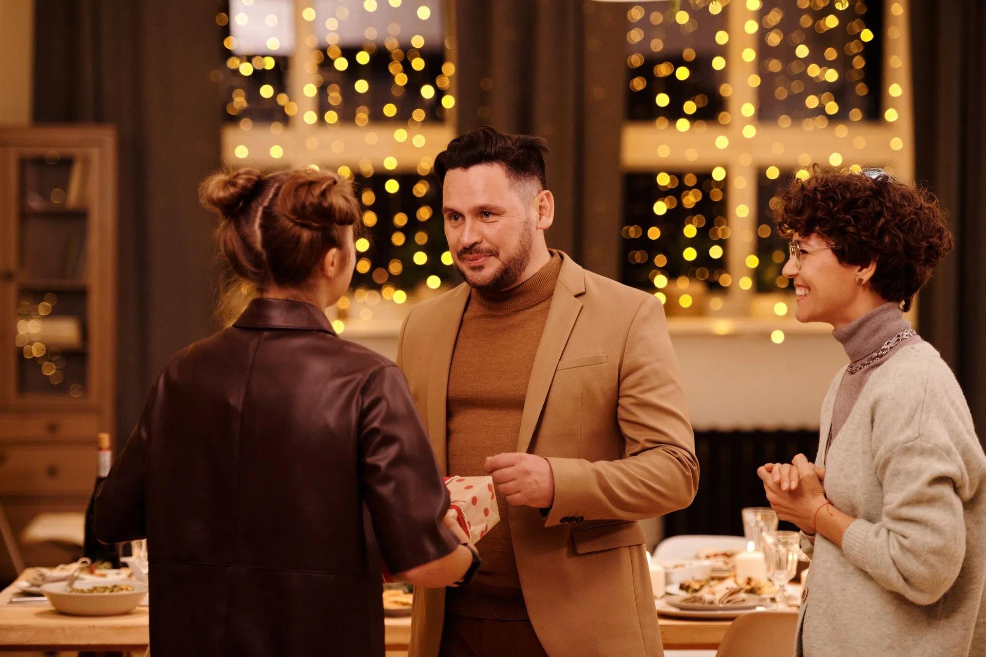 A woman giving a gift to the male host of the dinner party