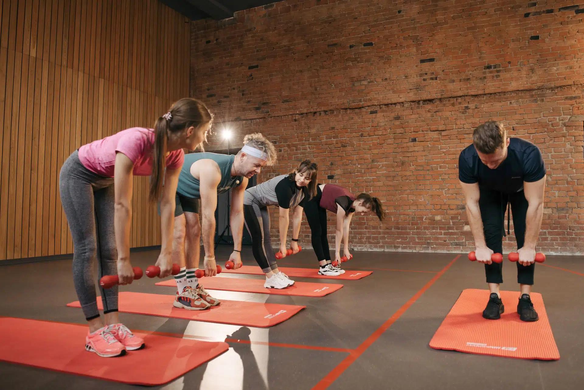 Fitness group performing exercises with dumbbells in a modern yoga studio setting