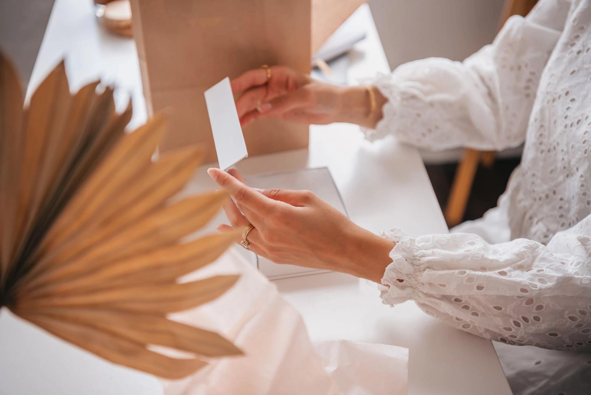 A person with lace long sleeves opening a white box at a table