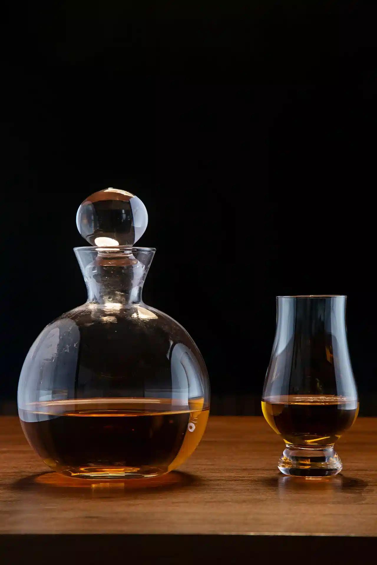 A round whiskey decanter and a Glencairn glass on a wooden table