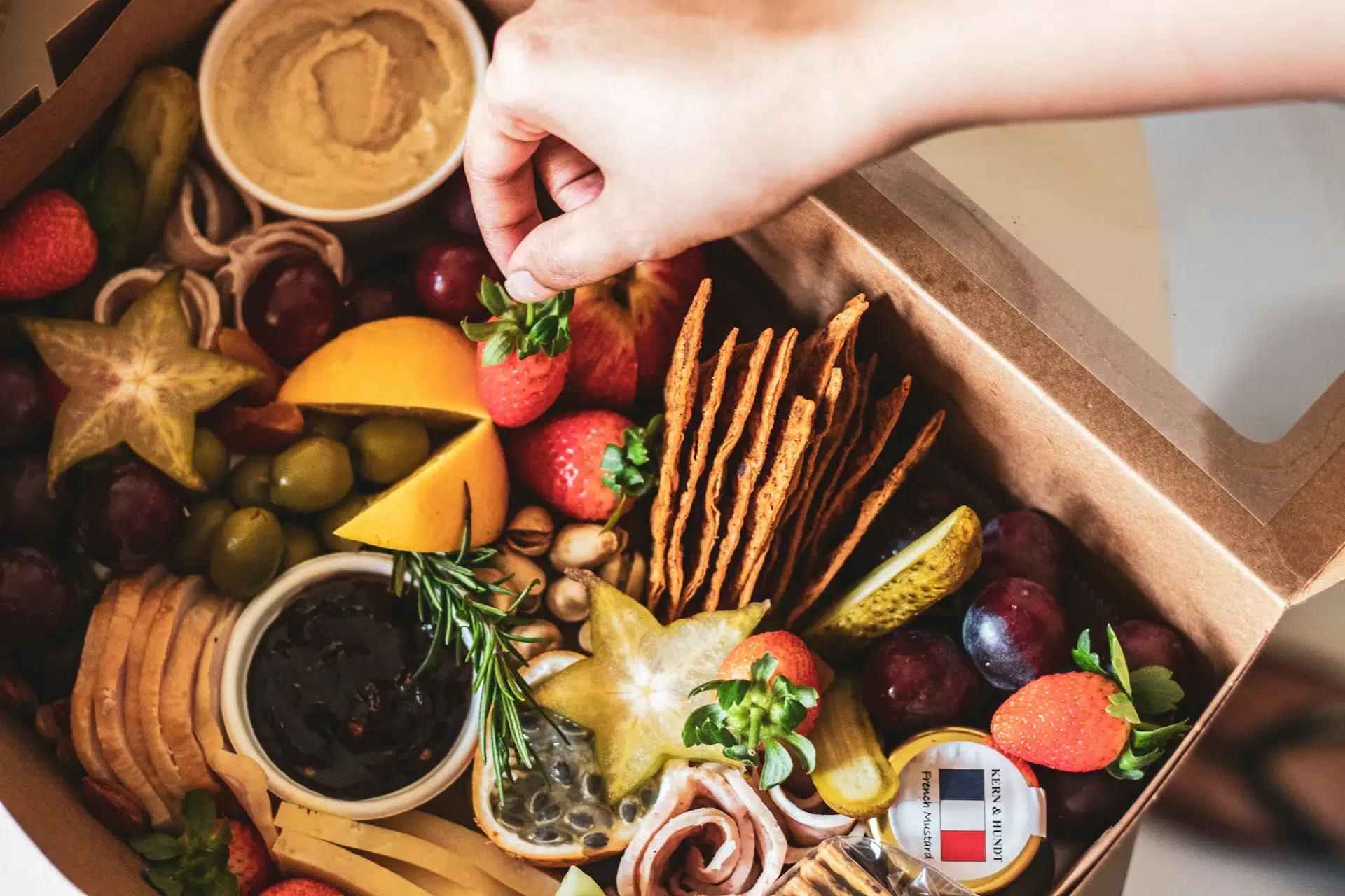 Image of a hand reaching into a box of gourmet food items