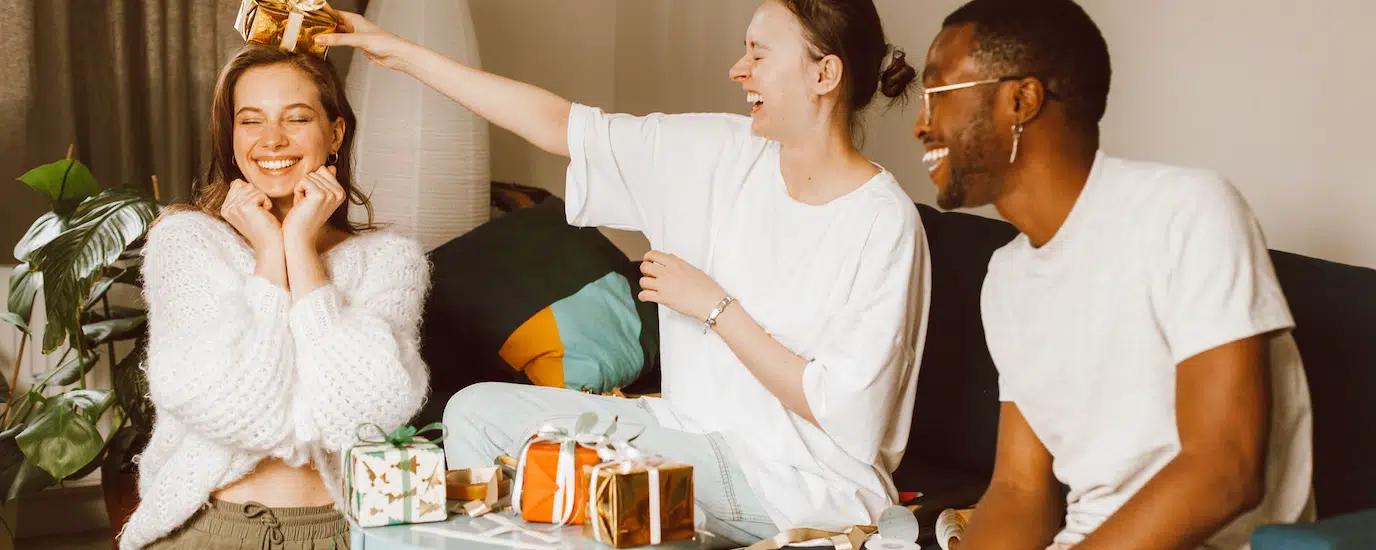 A cheerful group of diverse friends celebrating indoors, sharing laughter and gifts