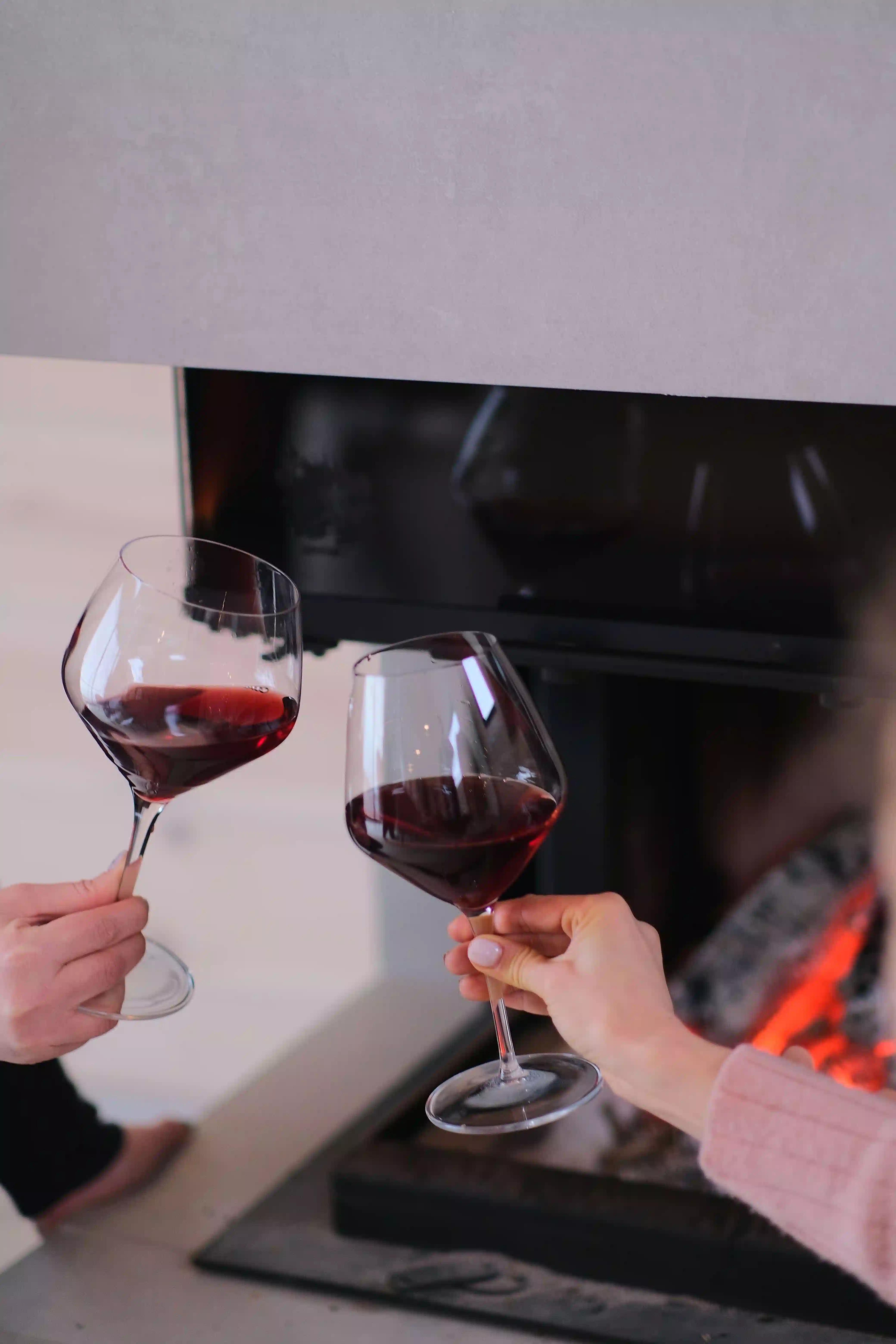 Two red wine glasses toasting