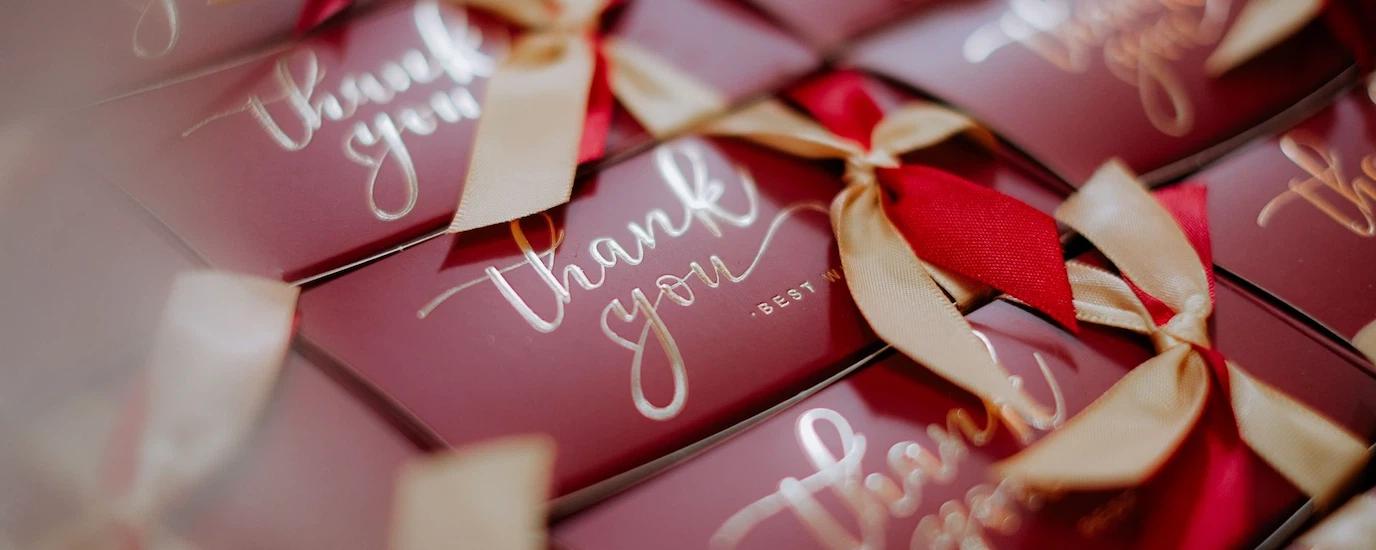 A close-up of beautifully wrapped red gift boxes with 'Thank you' tags and golden ribbons.
