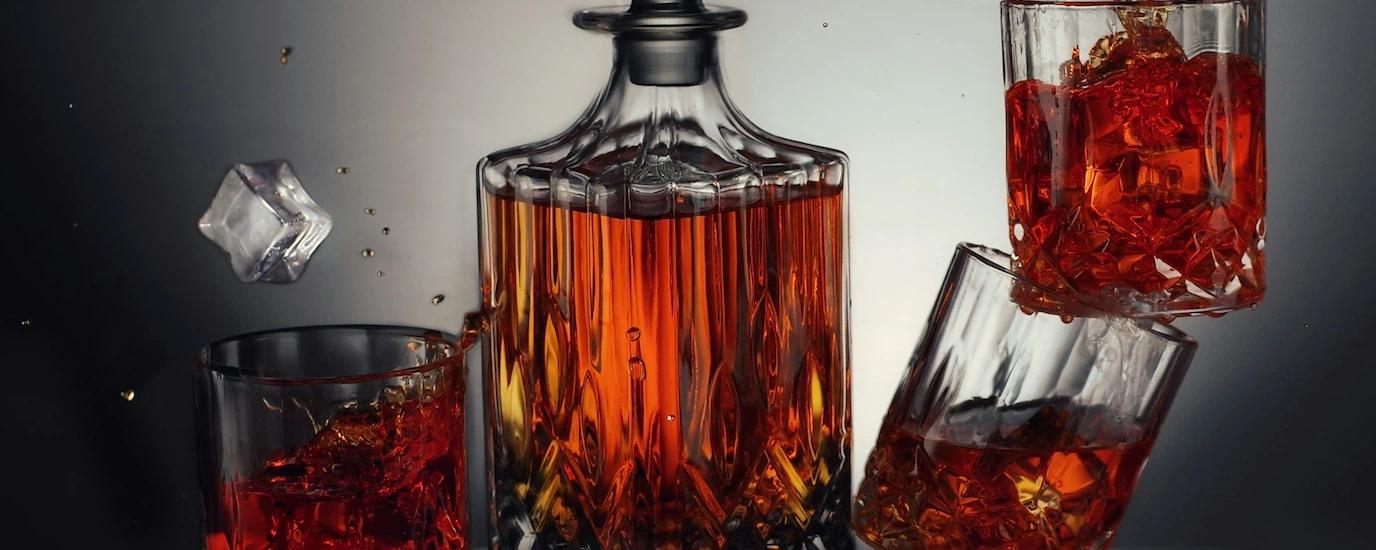 A whiskey decanter surrounded by whiskey glasses 