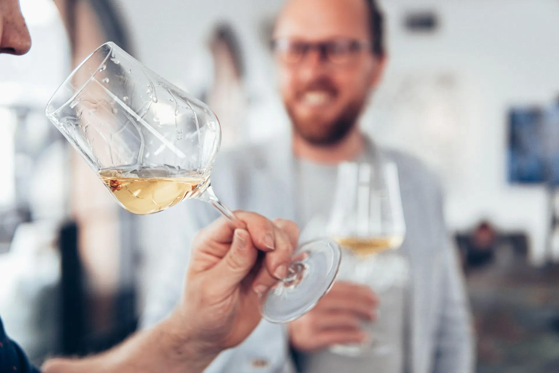 A man about to take a sip of his white wine
