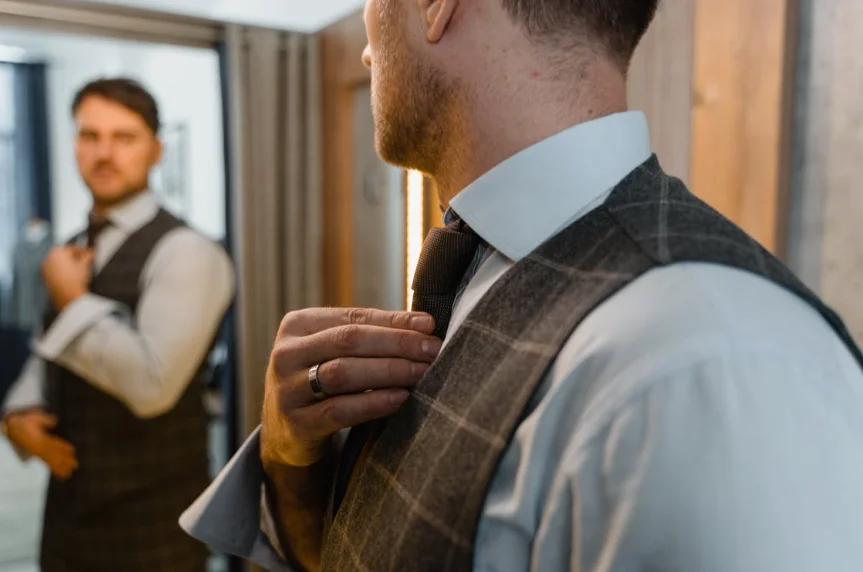 A nicely dressed man looking at himself in the mirror