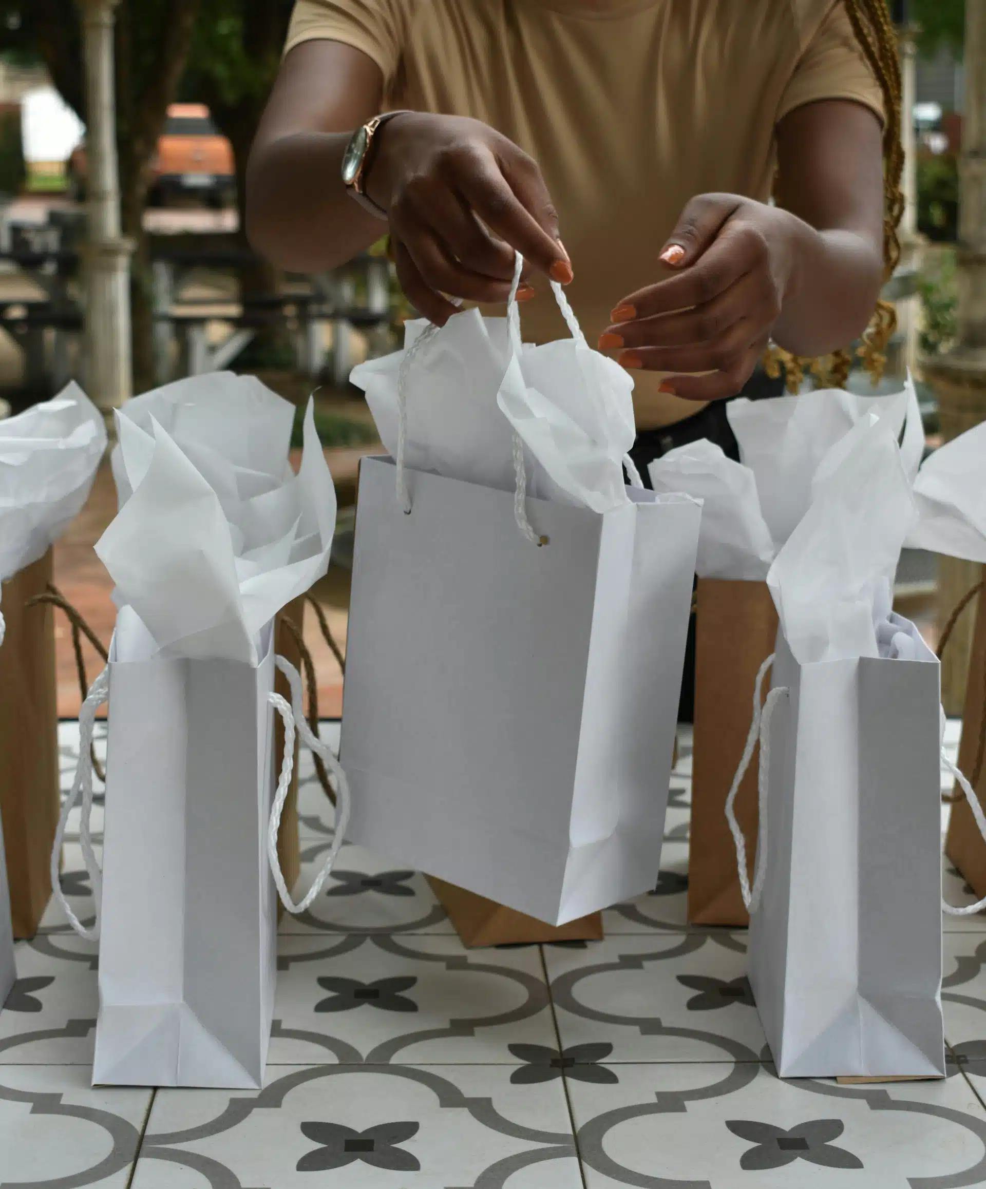 A woman reaching for a white gift bag on a table