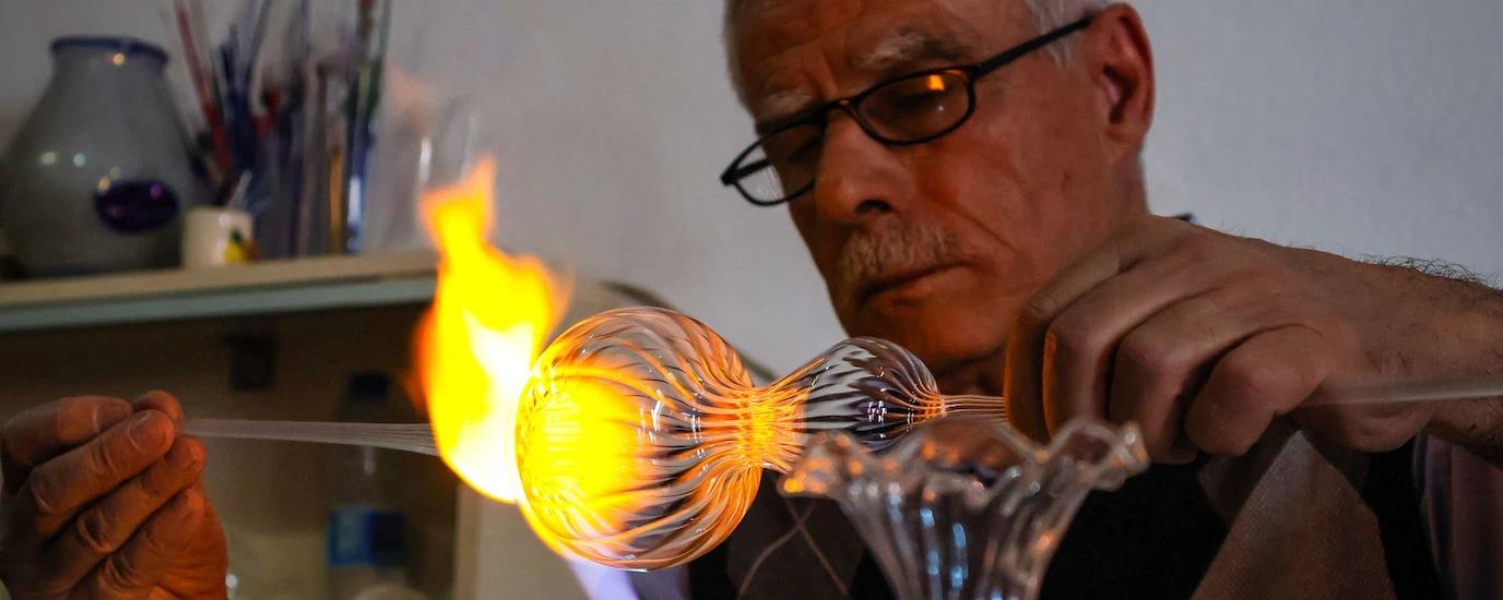 Skilled craftsman using fire to mold glass in a workshop environment
