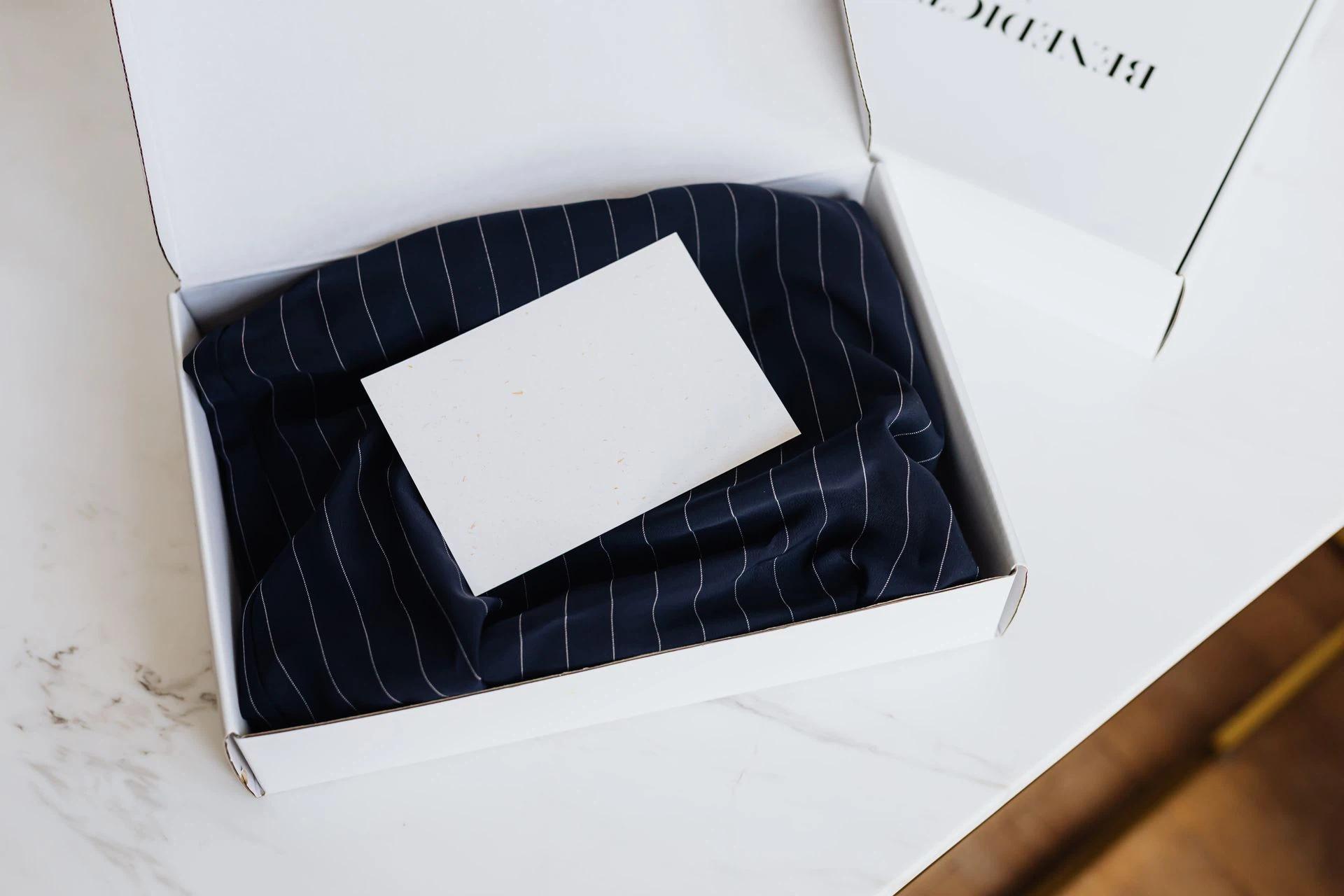 Minimalist white box with clothing and blank card on a marble table, ideal for branding