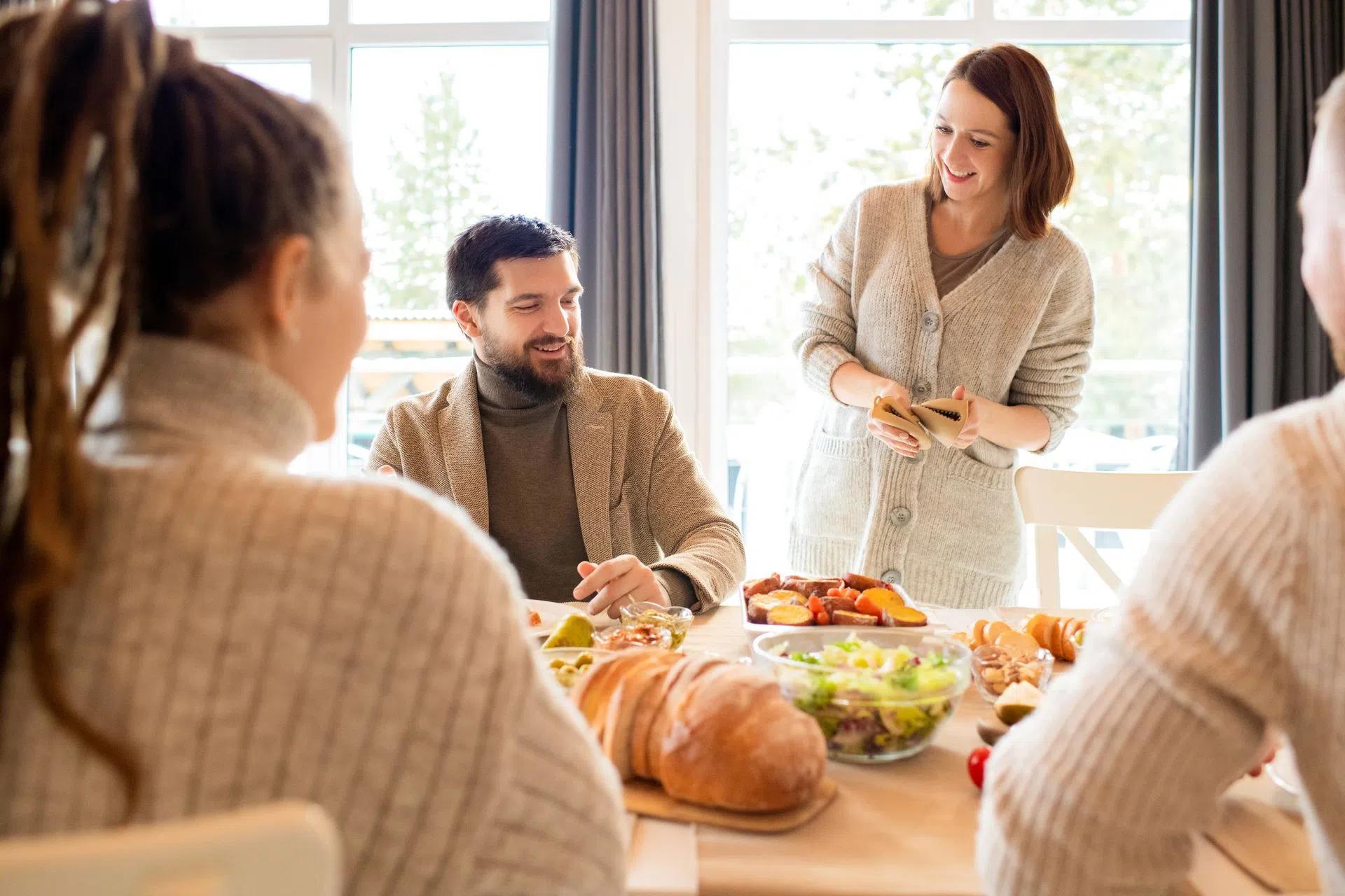 A cheerful family enjoys a casual meal in a modern, bright dining room setting with homemade food