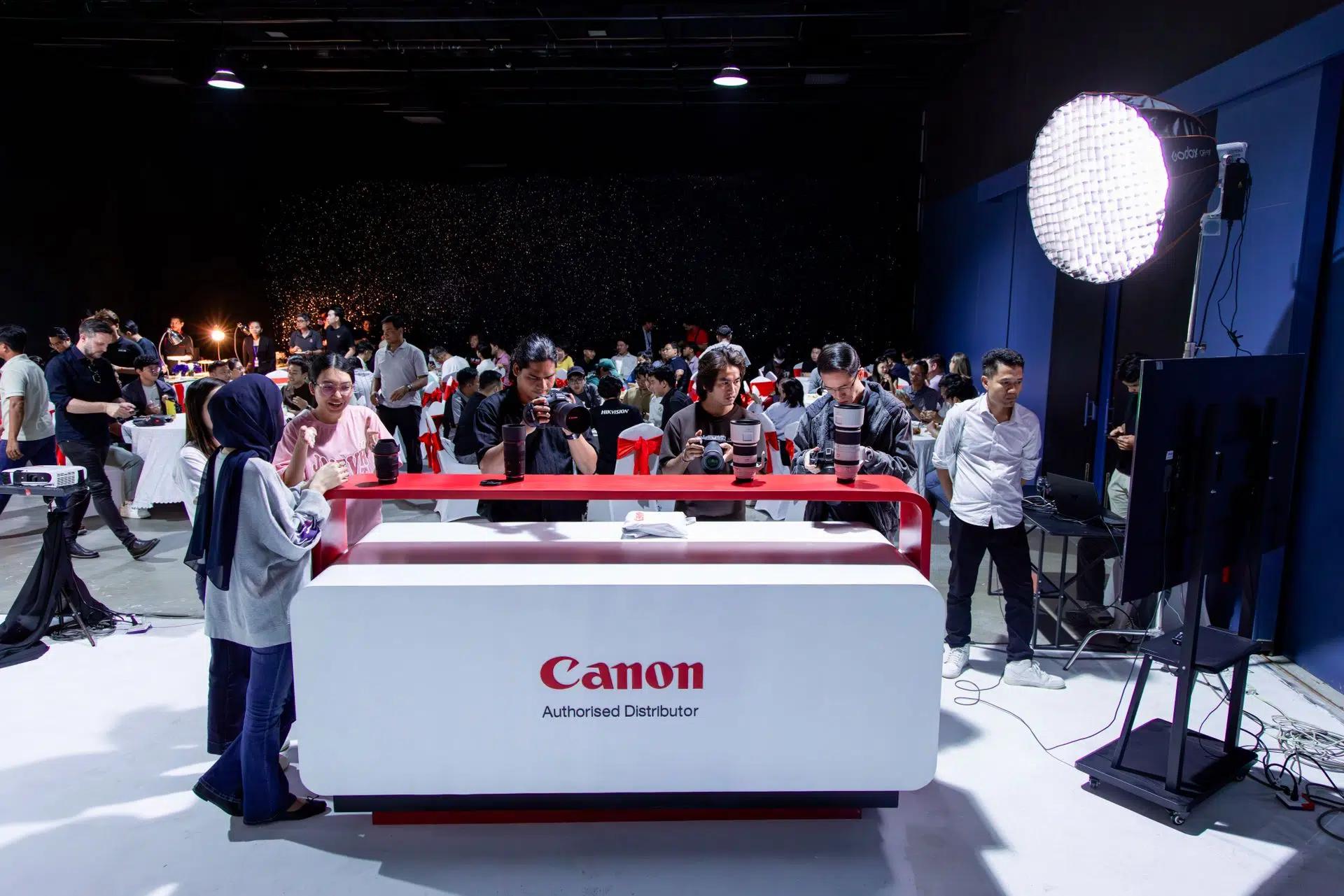 Photographers gather at a Canon photography workshop indoors, engaging with equipment