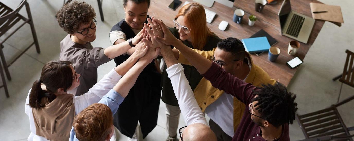 A diverse group of colleagues giving a high five during a corporate meeting indoors