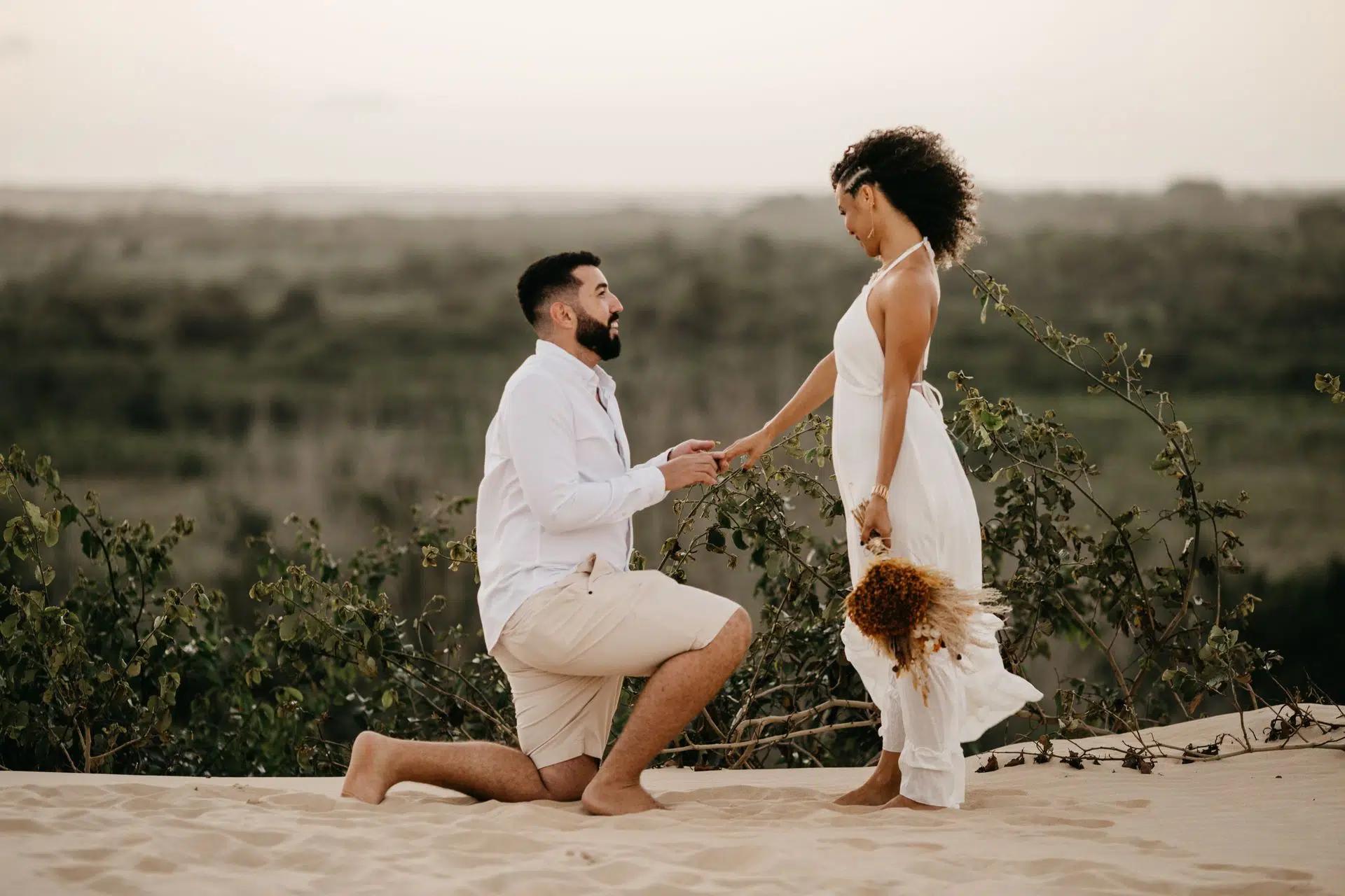 A man proposing to a woman on a sandy beach during sunset, capturing a romantic moment