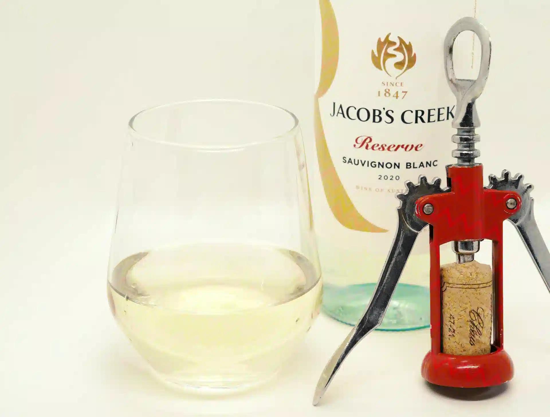 A bottle and a glass of Sauvignon Blanc and a corkscrew beside