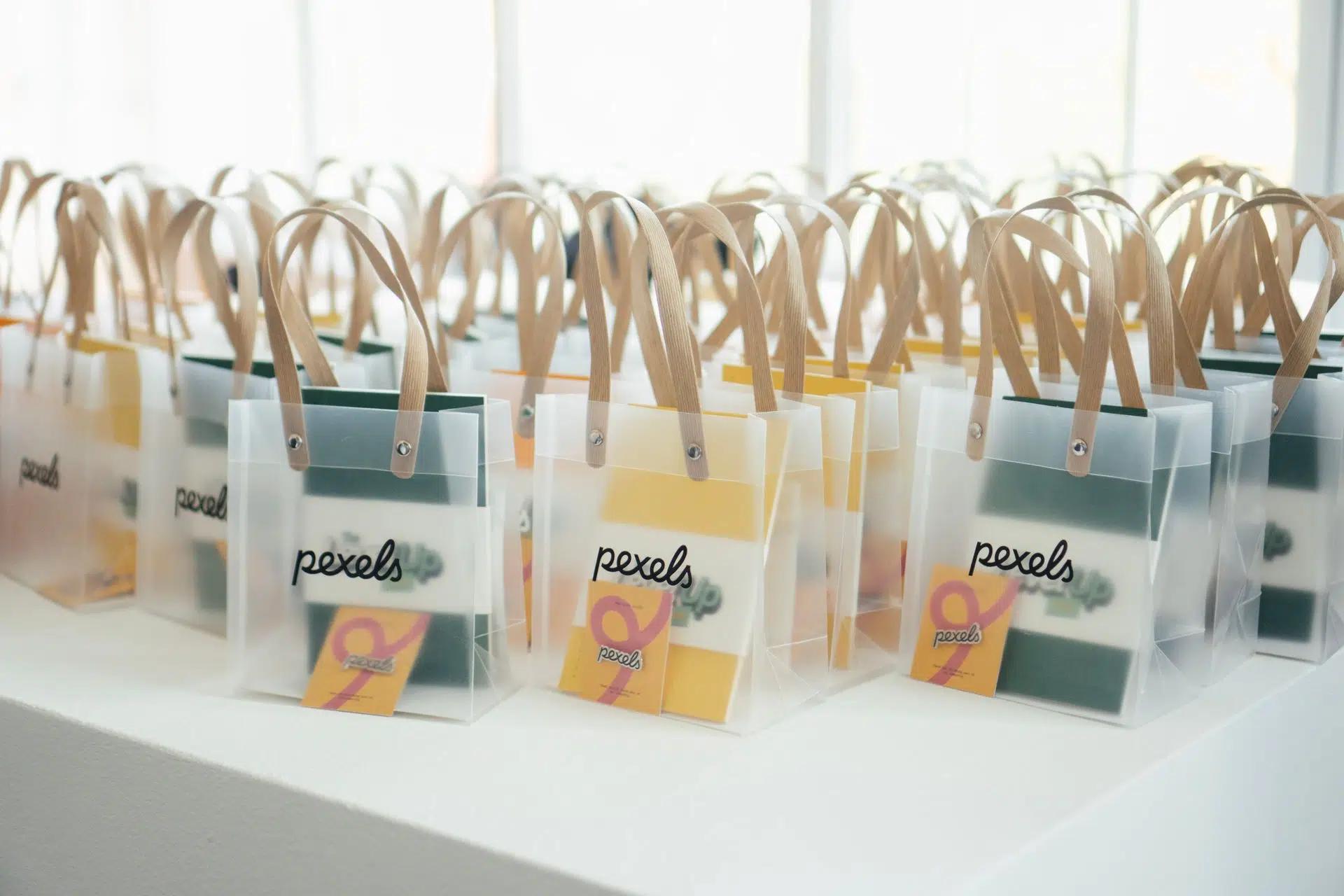 Rows of stylish gift bags with transparent design and wooden handles, ready for an event