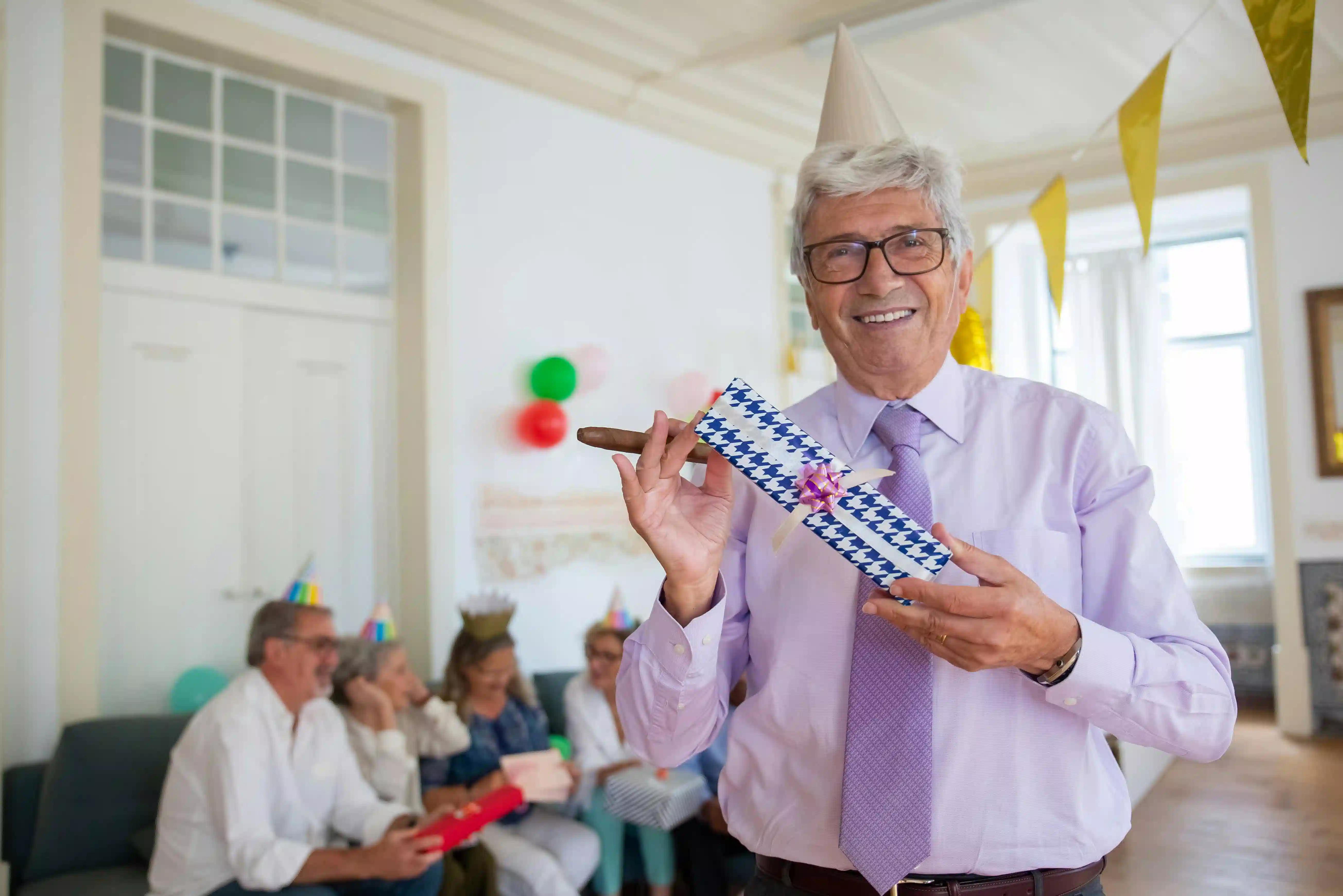 An older man happily holding a gift