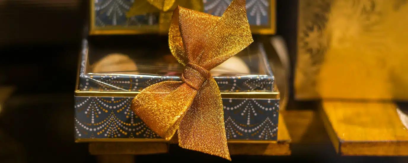 A blue and gold gift box with a large gold ribbon front and center