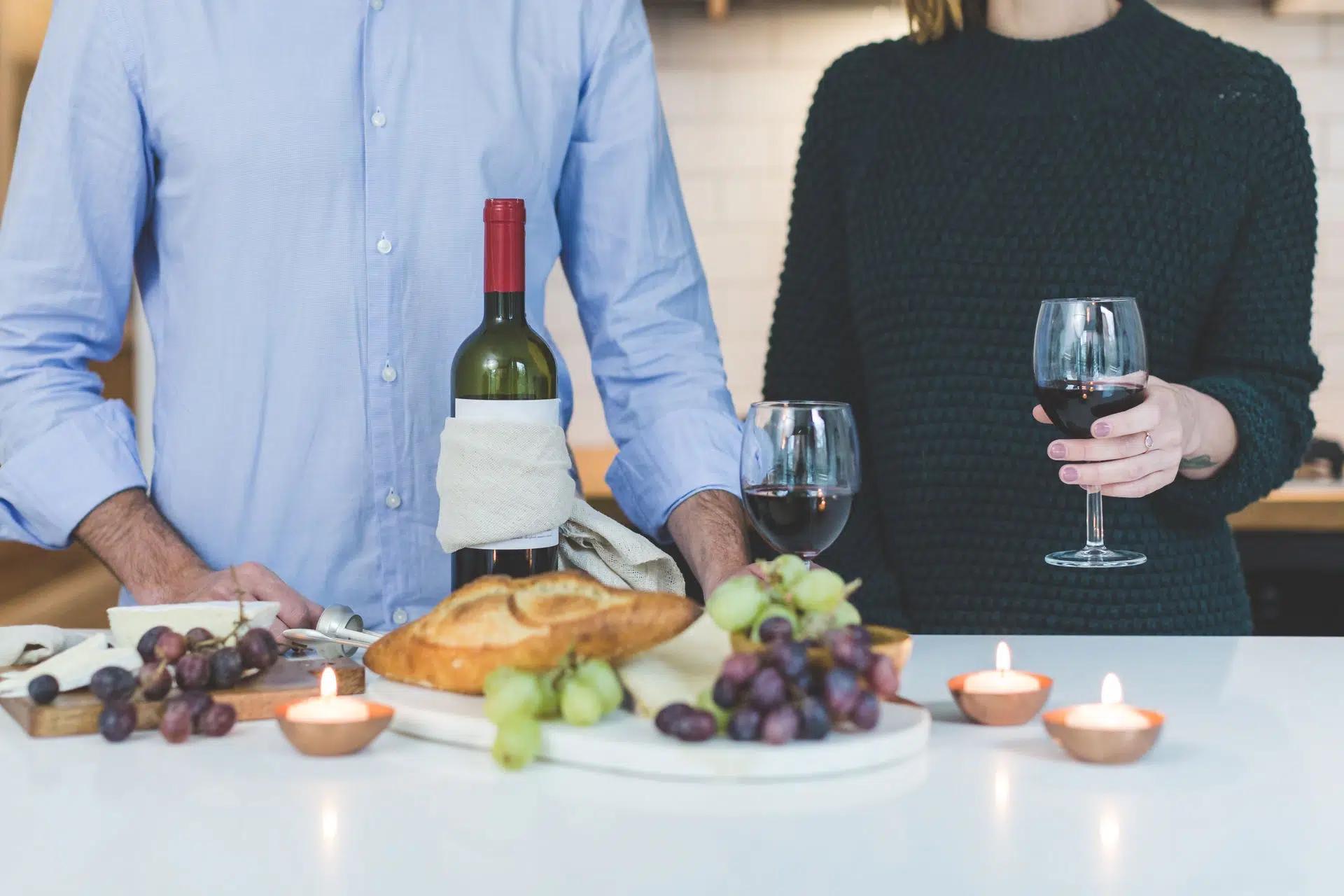 A couple shares wine and bread in a cozy indoor setting with candlelight