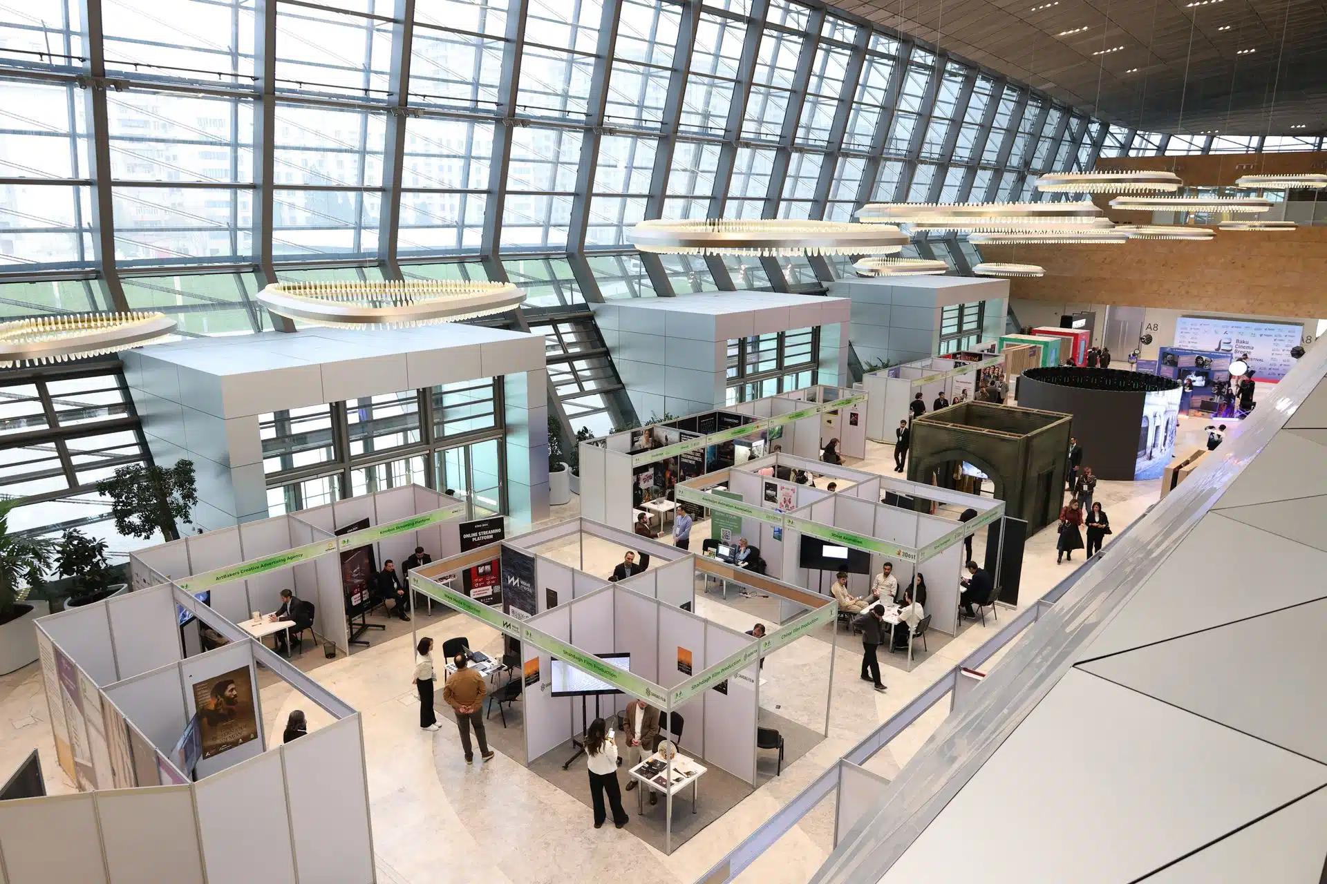 A bustling trade show exhibition inside a modern hall with people networking and exploring booths