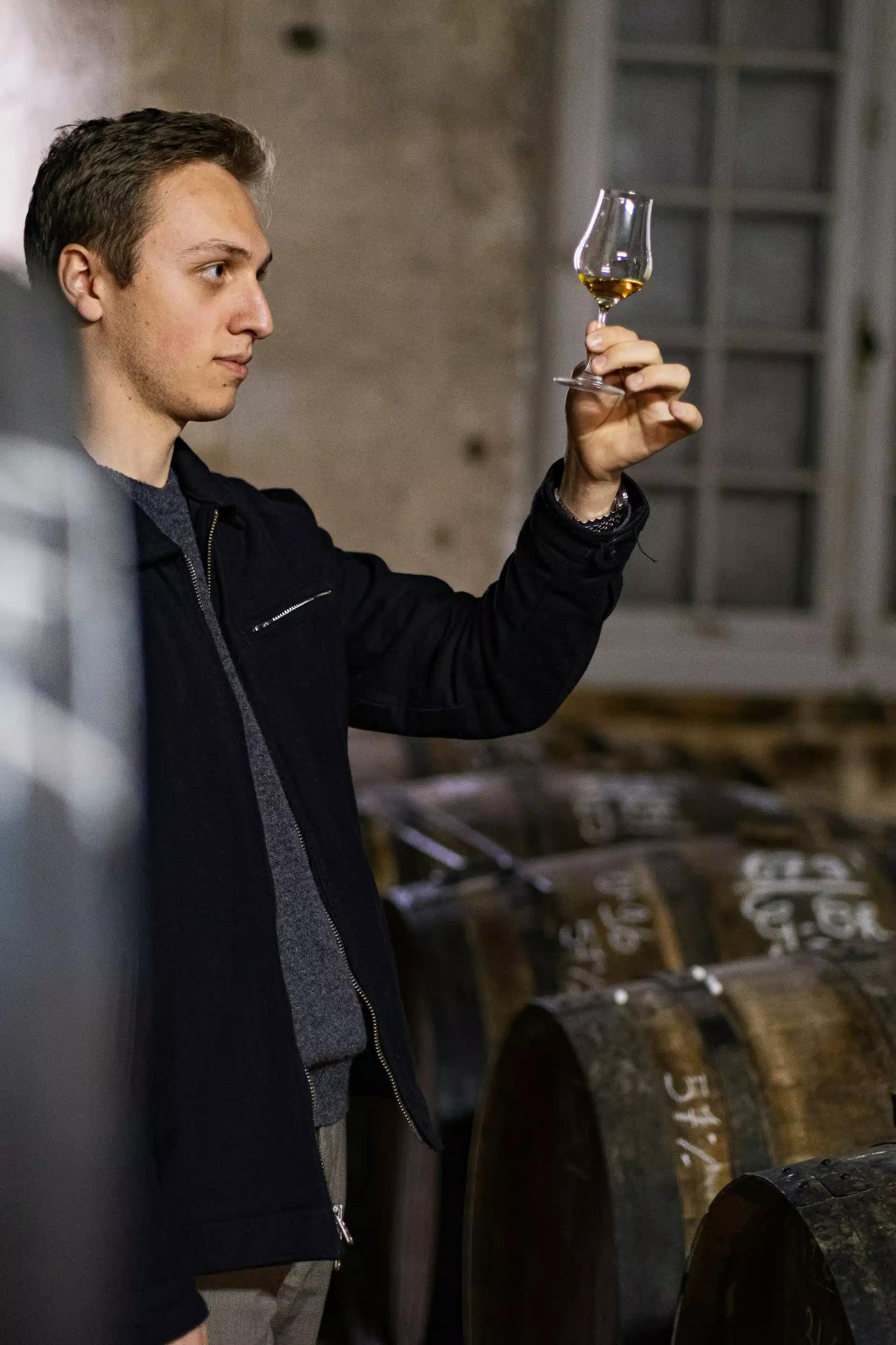 A man carefully inspecting a whiskey glass