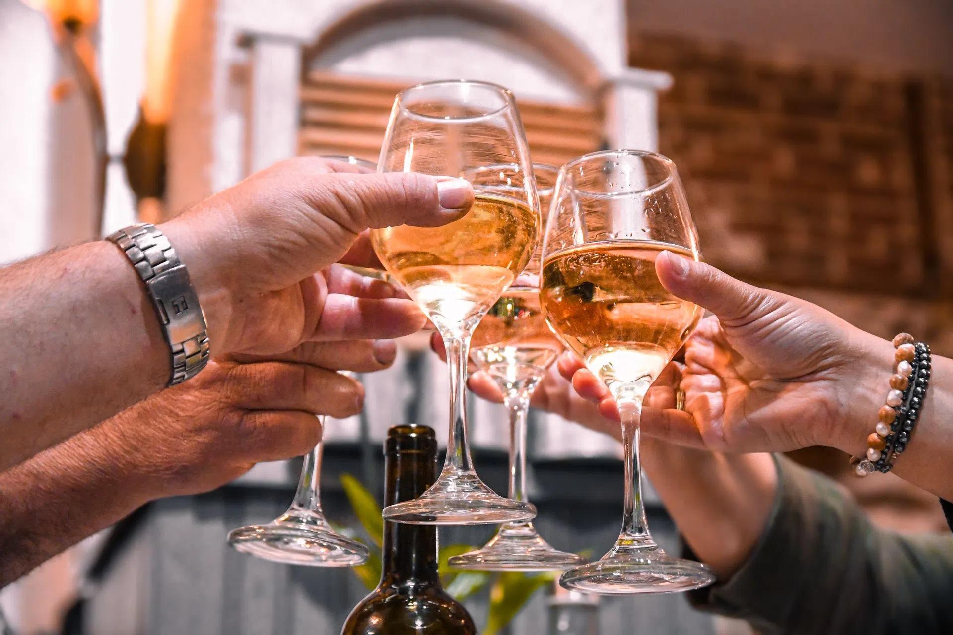 Close-up of friends toasting with white wine glasses in an indoor setting