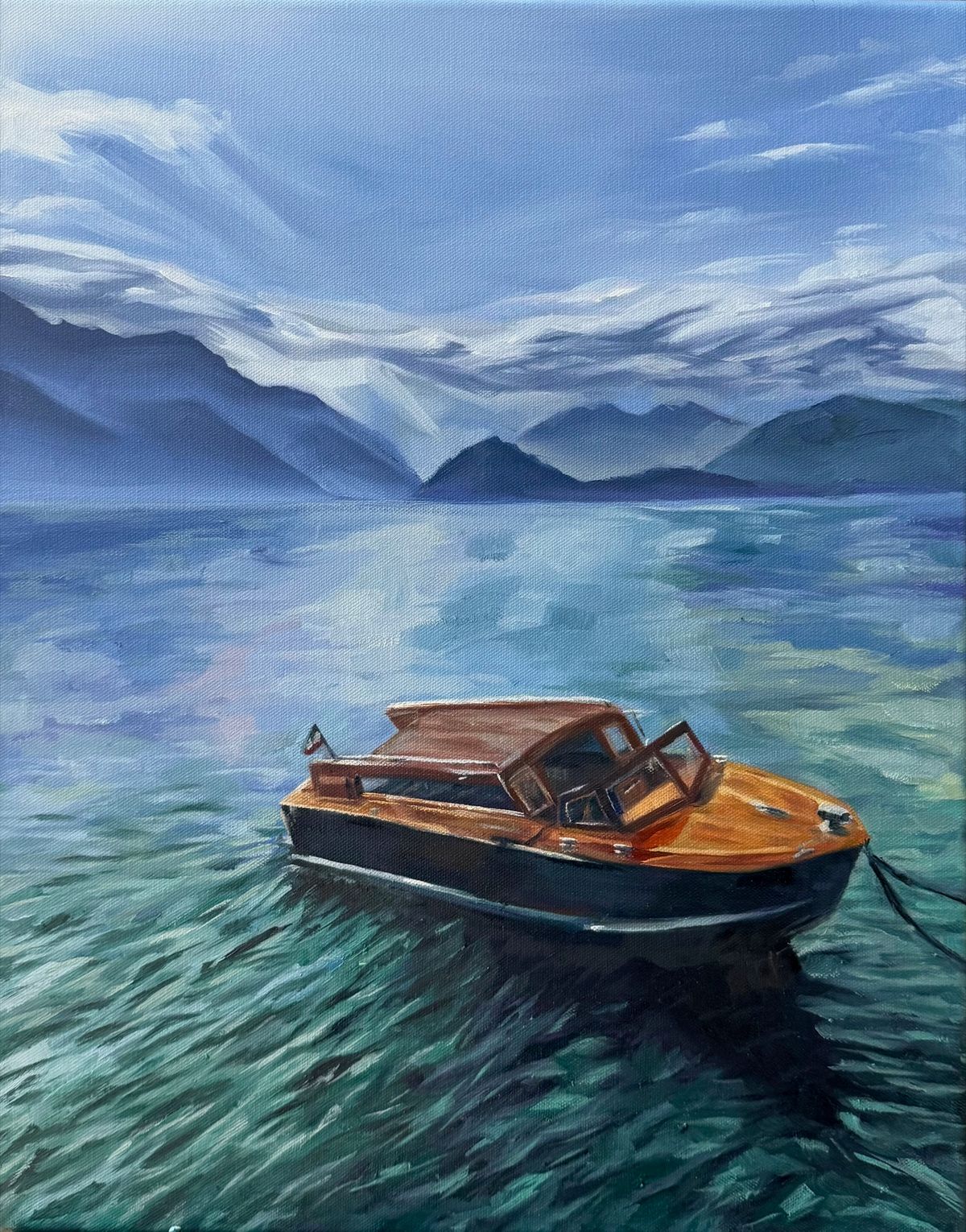 A wooden motorboat moored on clear green water below misty mountains