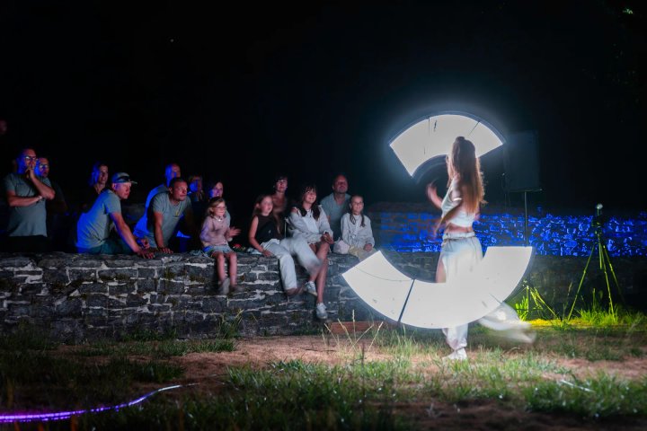 Lichtartieste met LED-waaier voor het publiek op de oude muur
