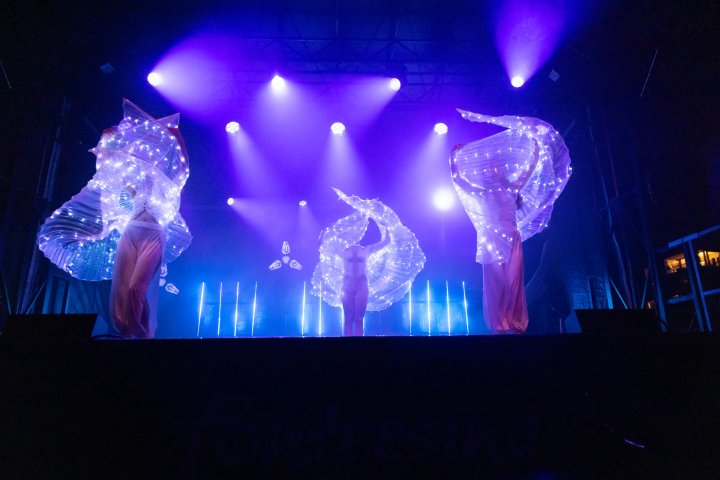 Dansers met lichtvleugels in paars en blauw licht